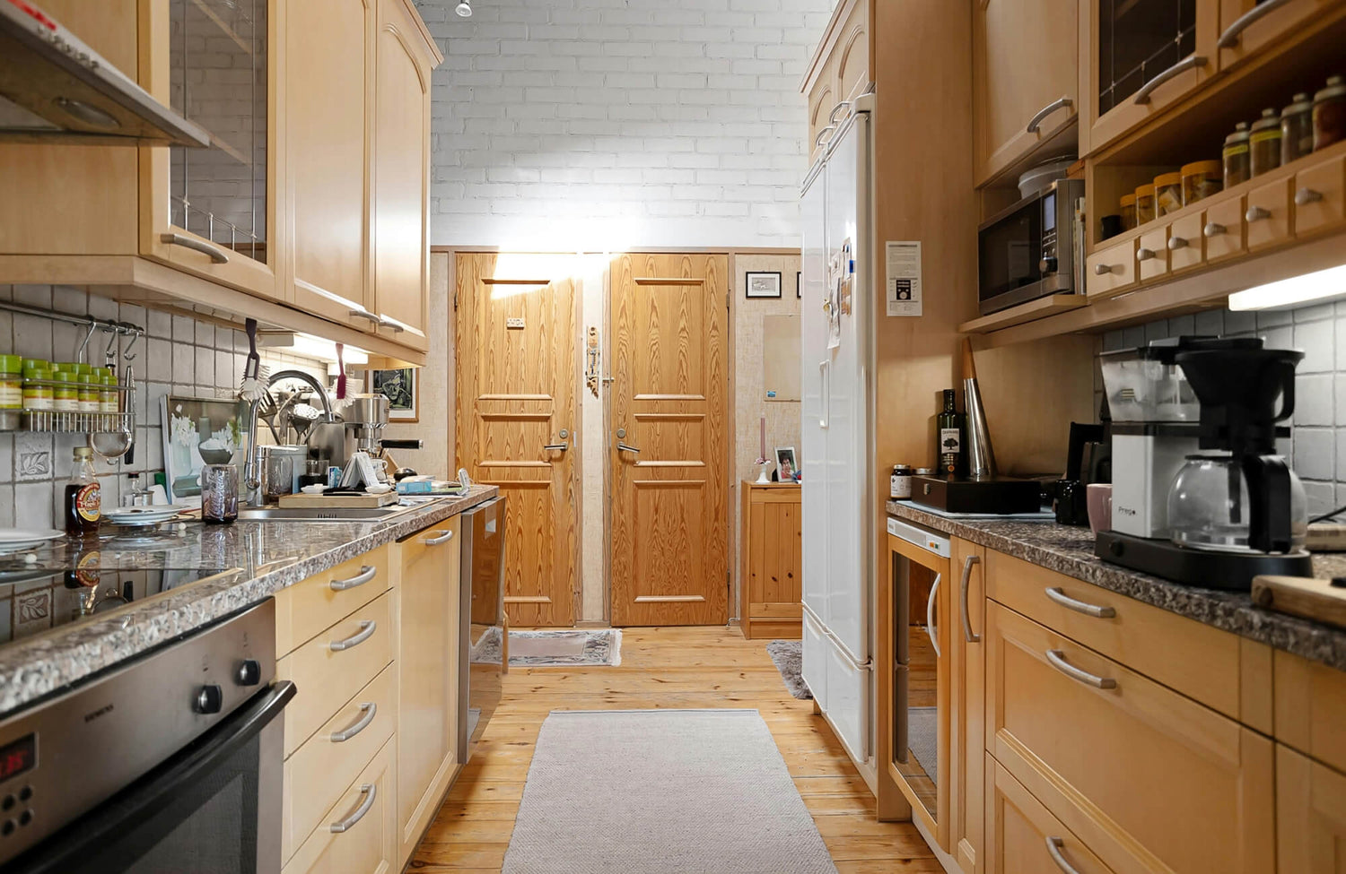 Bright kitchen with natural wood plank flooring and a protective runner rug placed along the walkway to help reduce wear and protect the floor from daily kitchen activity.
