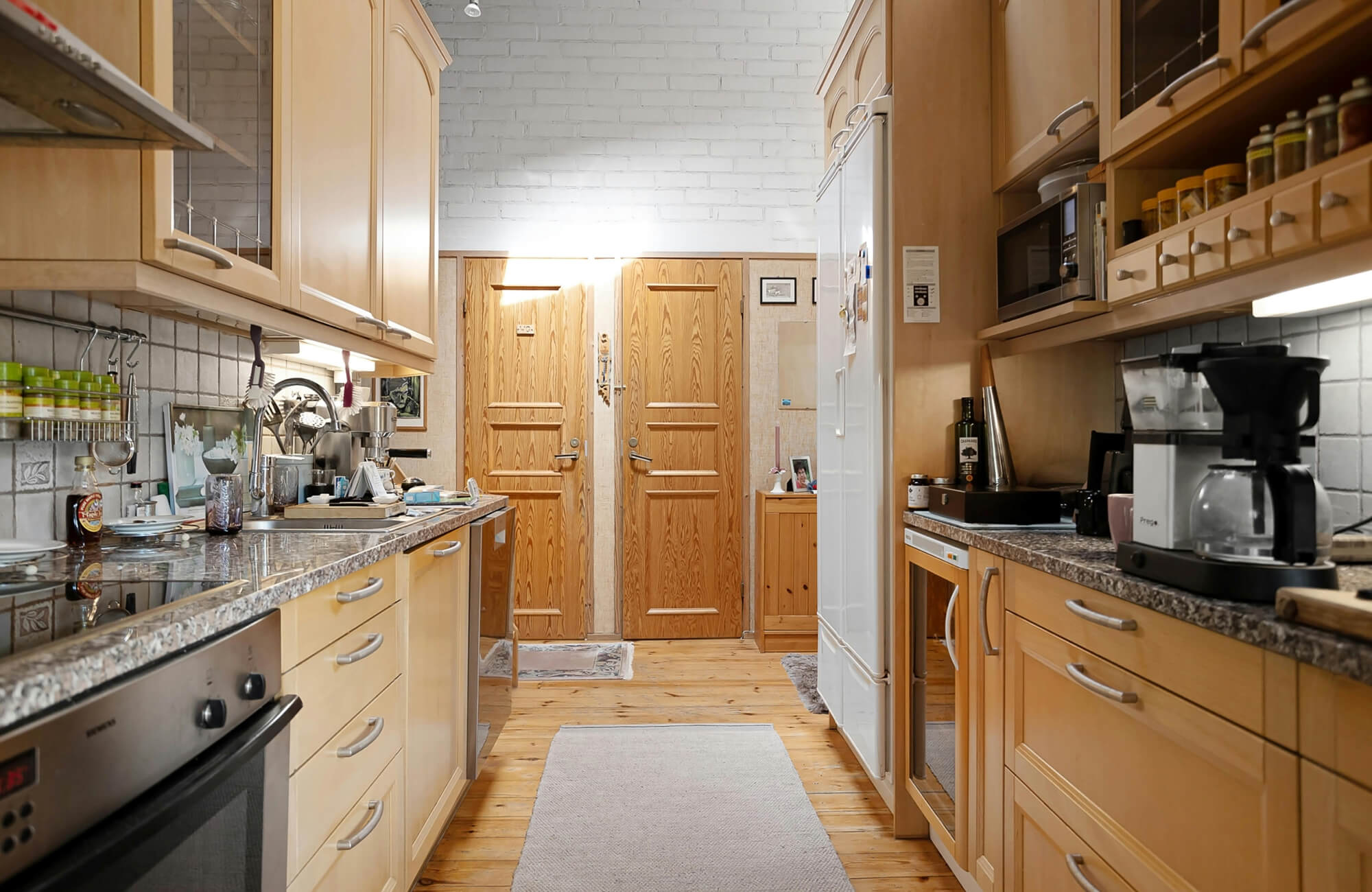 Bright kitchen with natural wood plank flooring and a protective runner rug placed along the walkway to help reduce wear and protect the floor from daily kitchen activity.