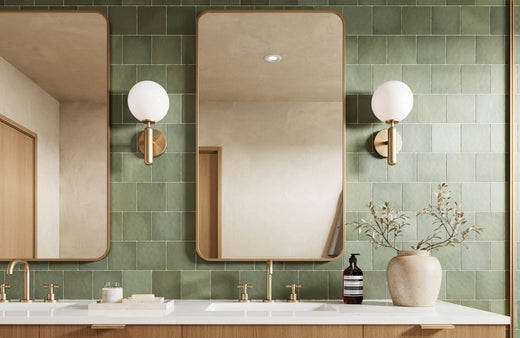 The modern bathroom features elegant green wall tiles with a soft matte finish, gold fixtures, and natural wood cabinetry for a serene and sophisticated look.