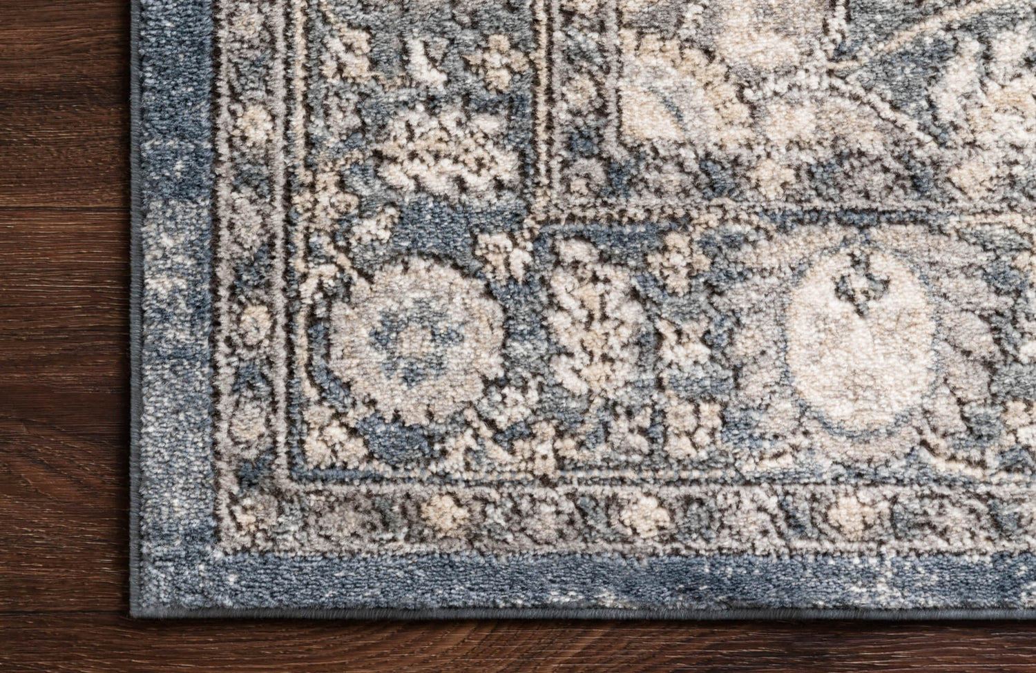 Intricately woven polypropylene rug with vintage floral motifs in muted blue and ivory, offering timeless charm and durability.