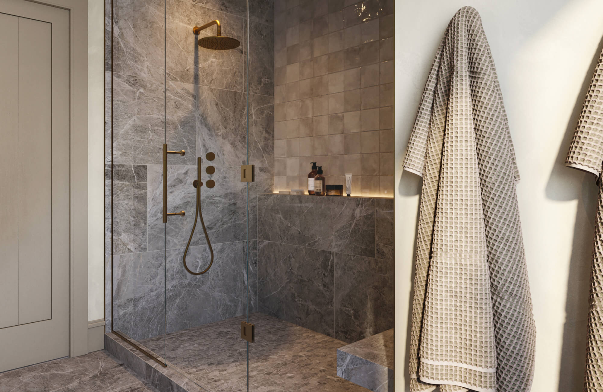 Luxurious walk-in shower featuring grey marble look tiles, warm brass fixtures, and a niche with glossy square wall tiles and soft lighting.