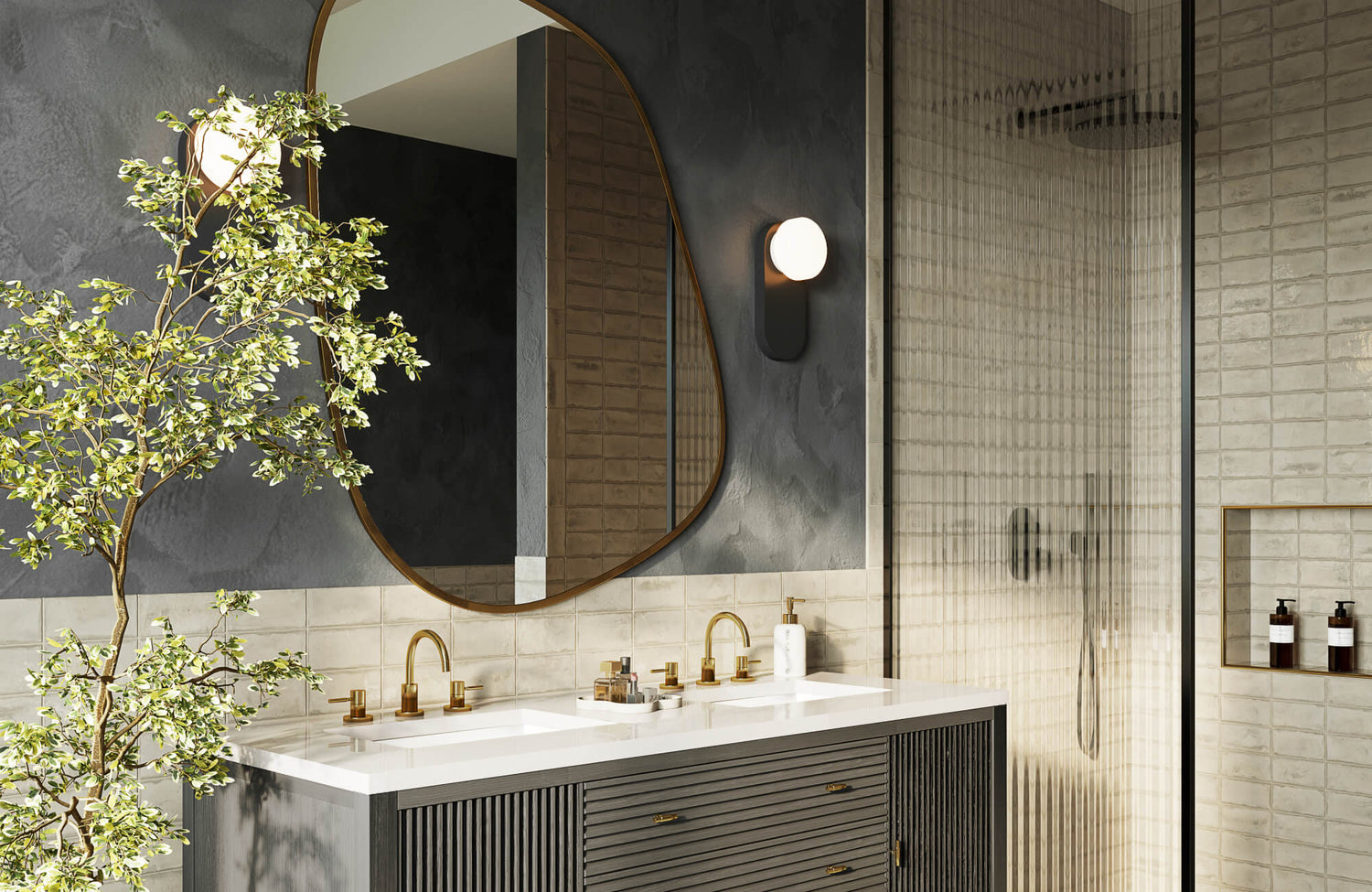 Modern double vanity with an organic-shaped mirror in a thin brass frame, paired with warm globe lighting, brass hardware, and softly textured tile surfaces.