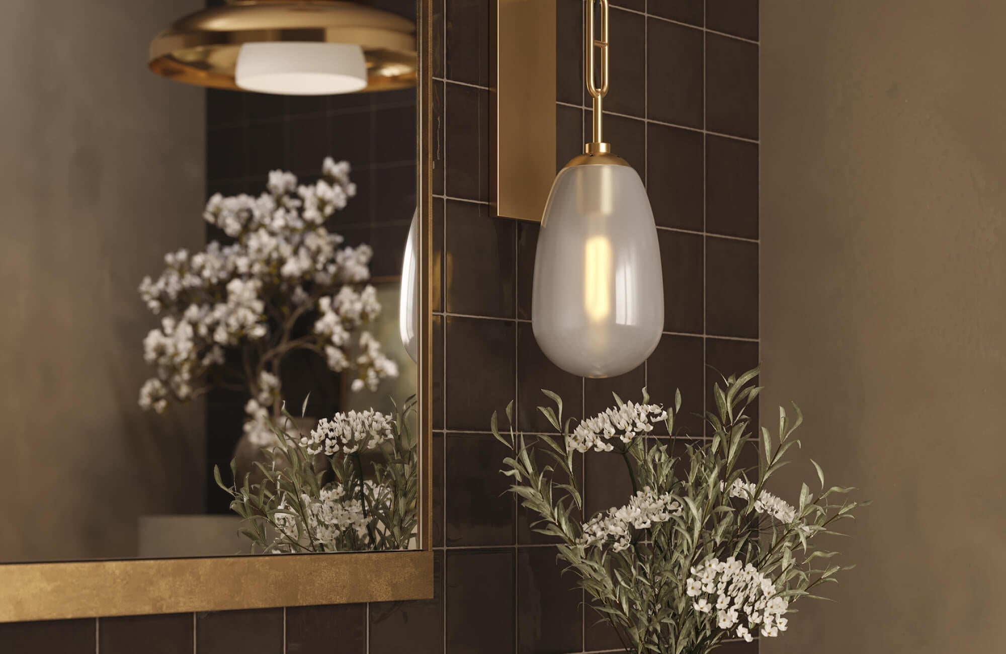 A pendant light beside a framed bathroom mirror illuminating surrounding tiles and decor.