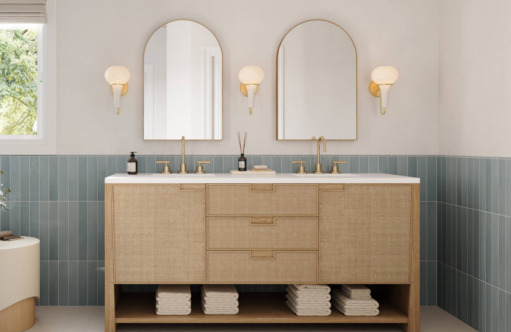 Arched mirrors with brass sconces above a woven-front vanity and soft blue vertical tile backsplash