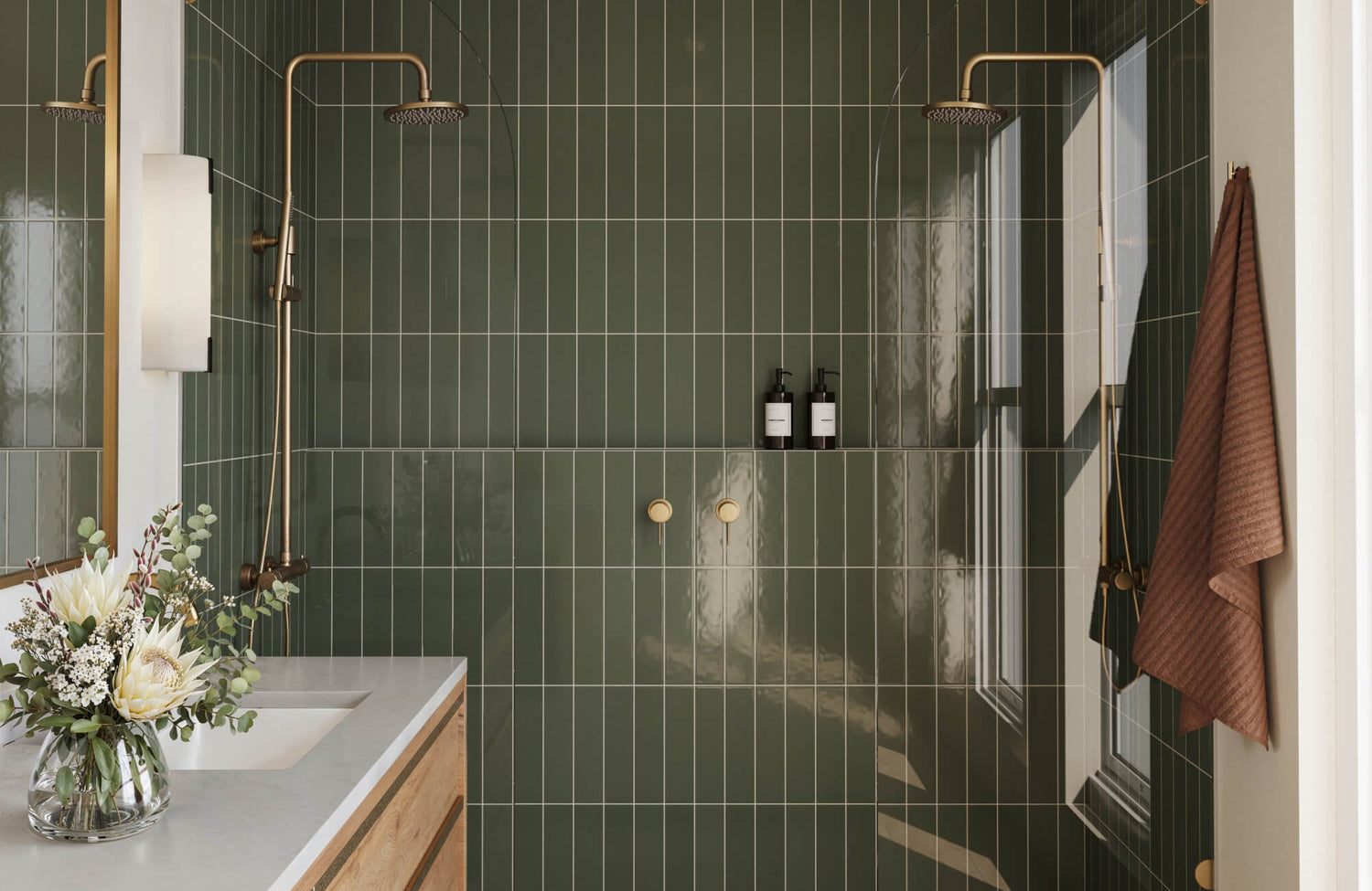 Contemporary bathroom with glossy forest green vertical tiles, dual brass showers, and light wood vanity.
