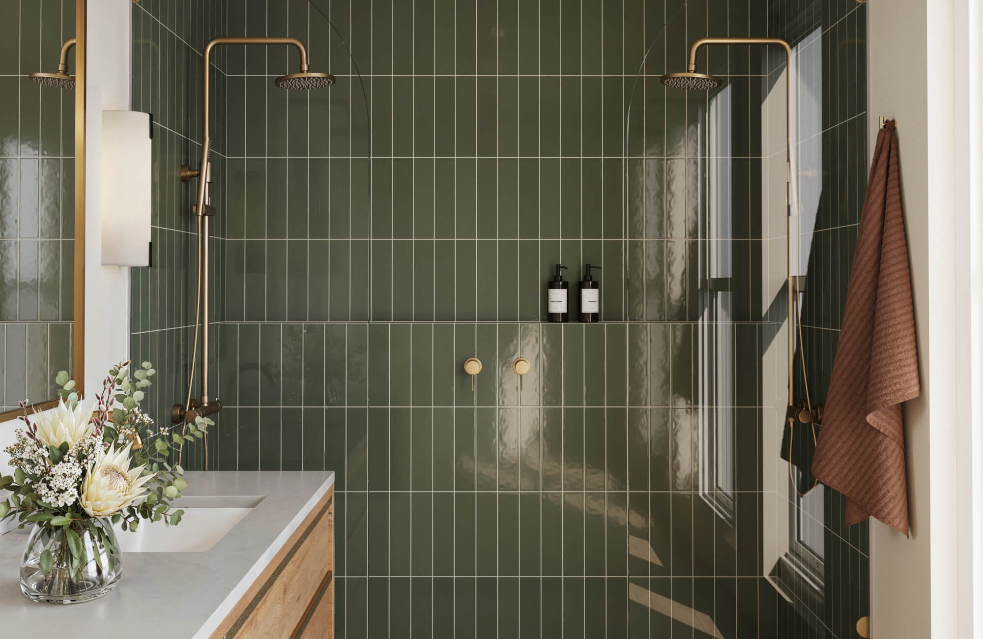 Contemporary bathroom with glossy forest green vertical tiles, dual brass showers, and light wood vanity.