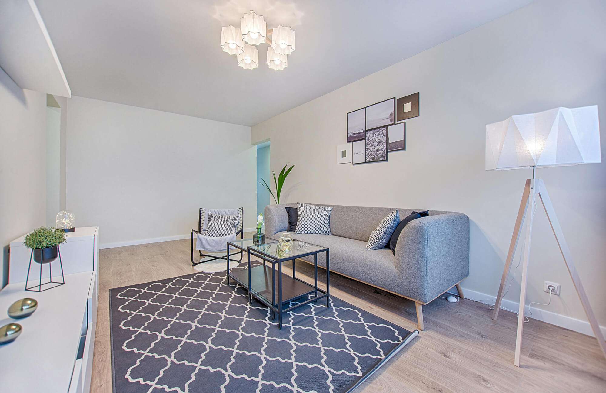 Modern living room with gray sofa, geometric rug, and minimalist lighting accents.