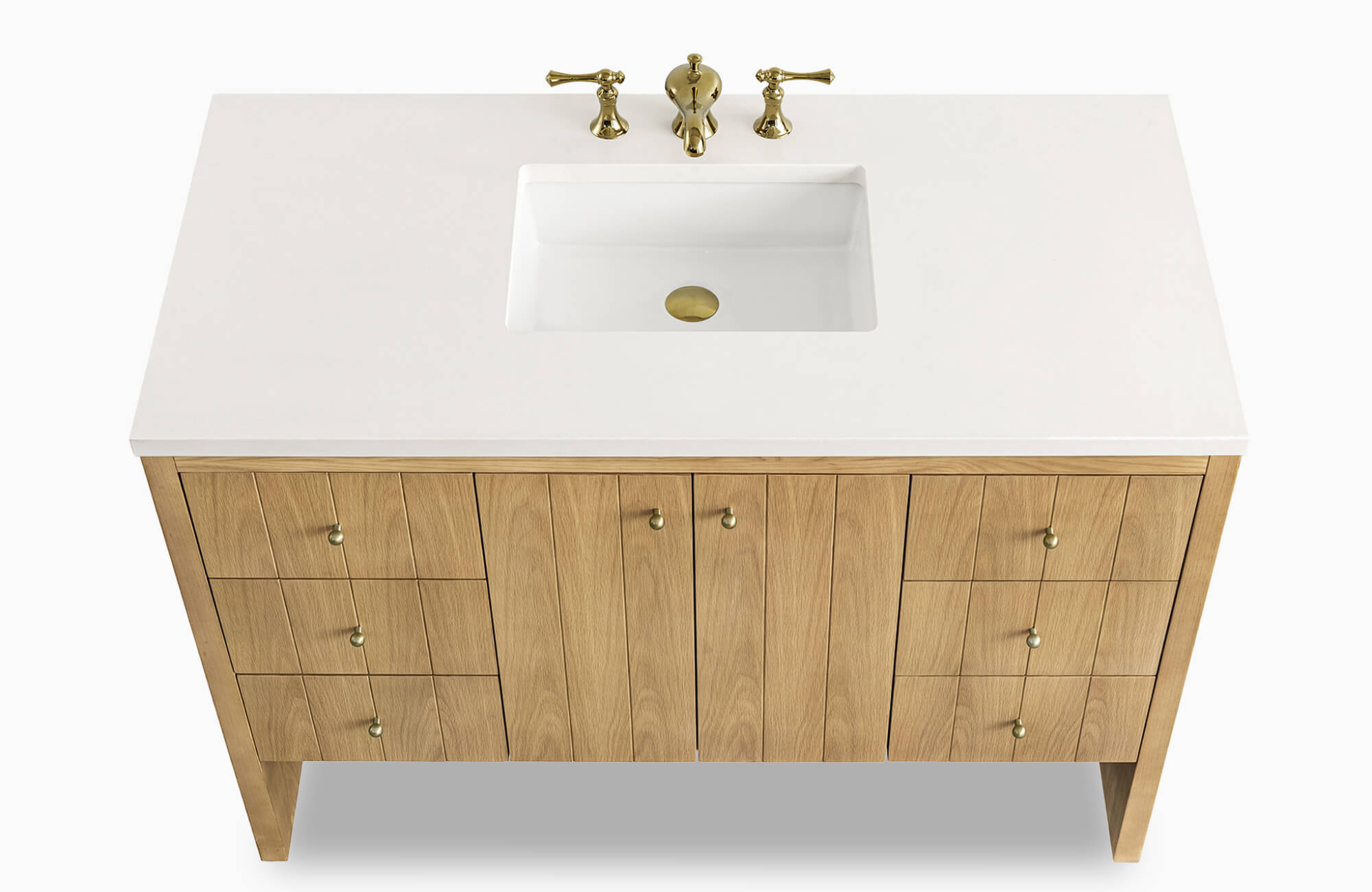 Bathroom vanity featuring a natural oak finish with brass knobs, a white integrated countertop and sink, and a three-piece brass faucet set.