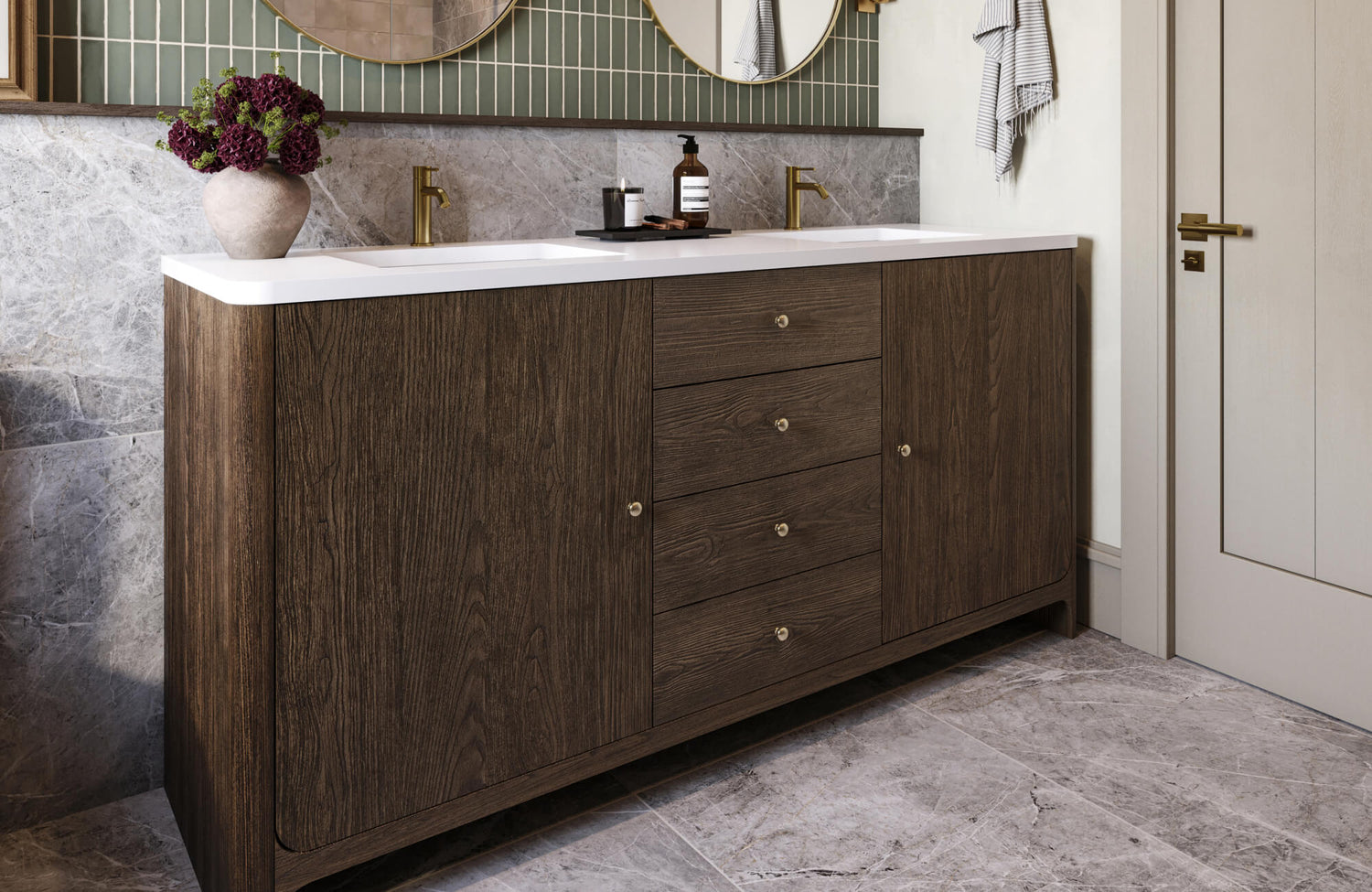 Contemporary bathroom vanity in rich wood grain with dual sinks, gold fixtures, and a white countertop set against marble and tile accents.