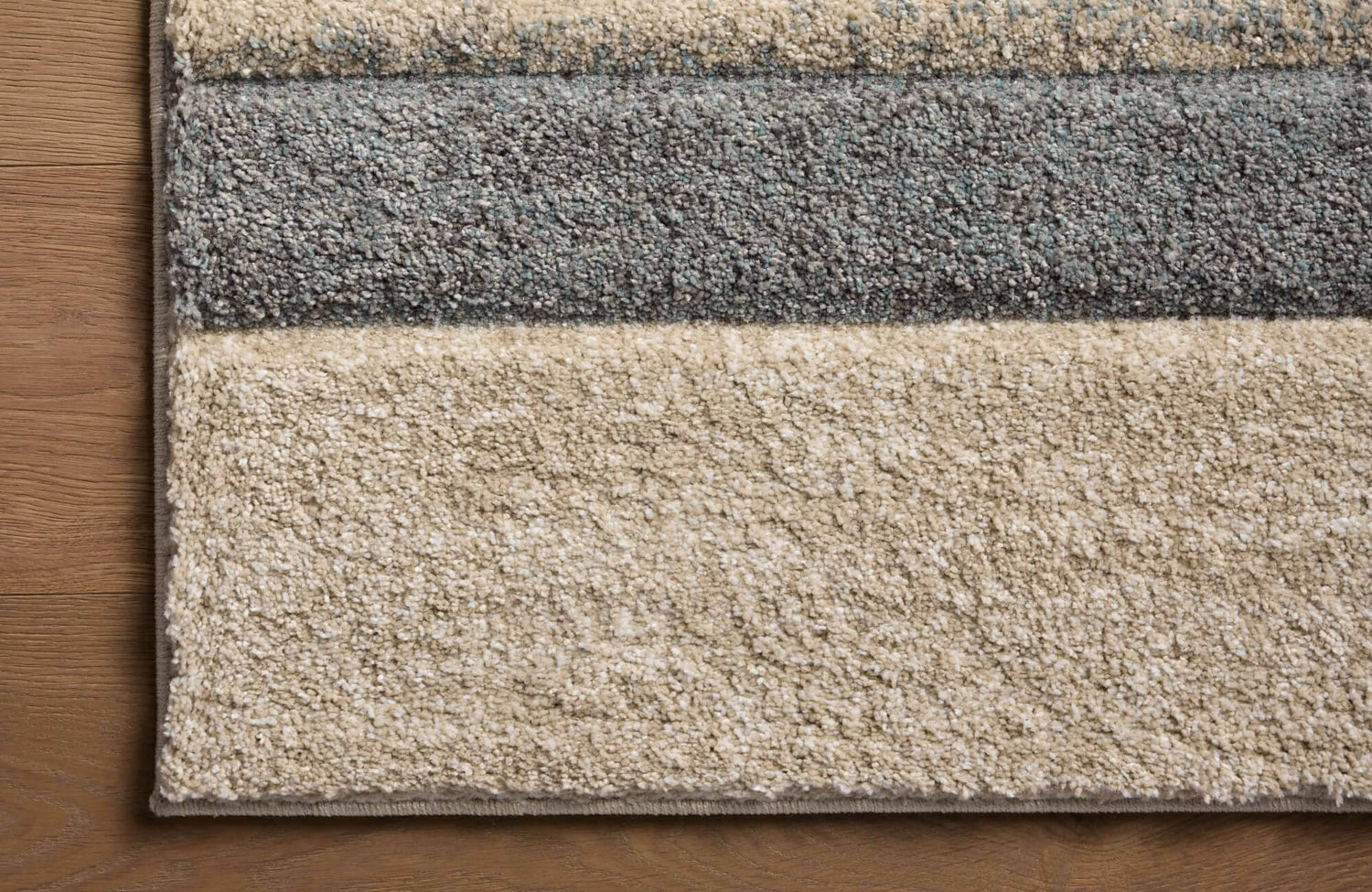 Close-up of the Broderick Polypropylene Pile Rug in Lake / Bone, showcasing its plush texture and striped design in neutral beige and gray tones.