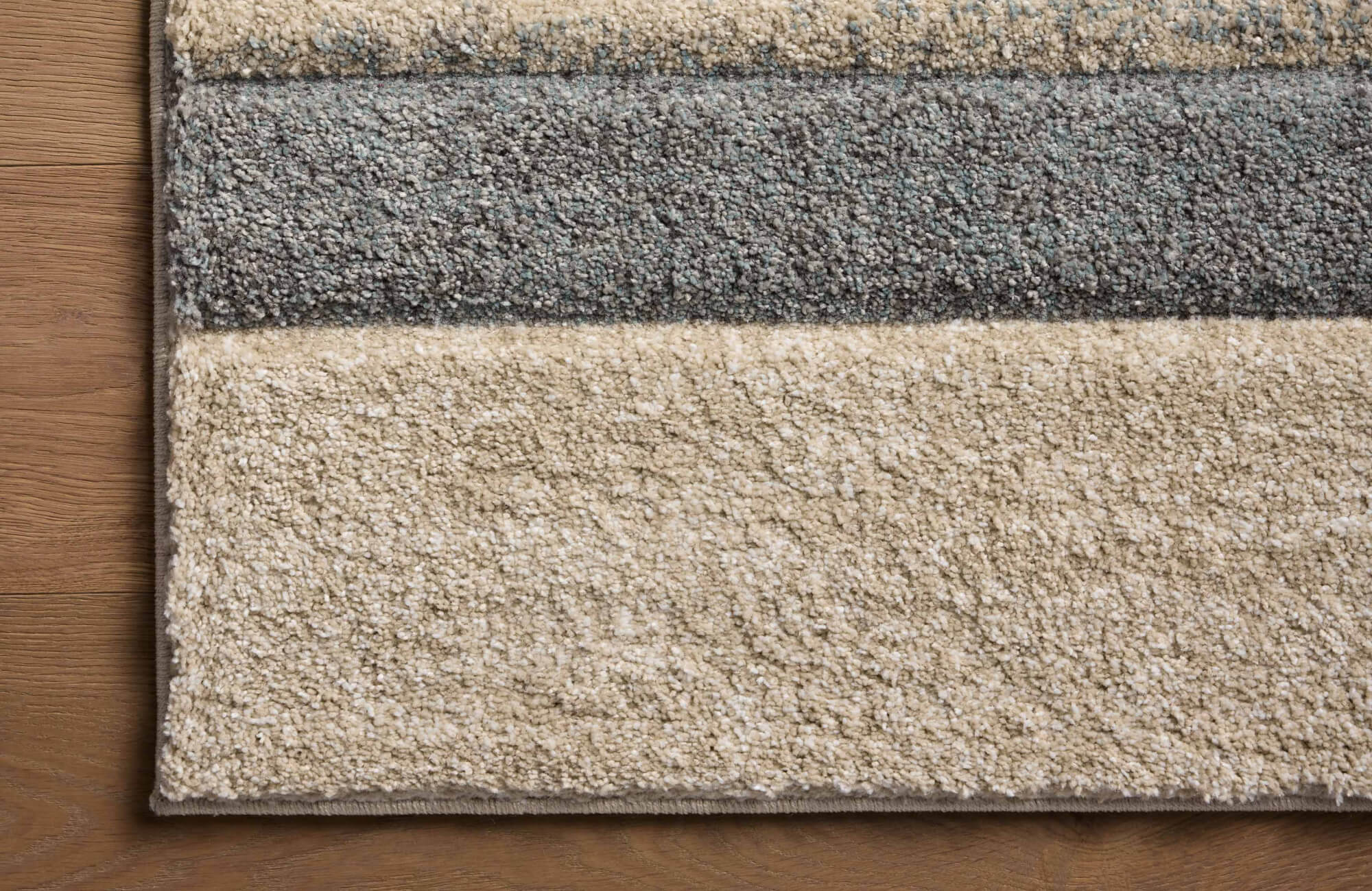 Close-up of the Broderick Polypropylene Pile Rug in Lake / Bone, showcasing its plush texture and striped design in neutral beige and gray tones.