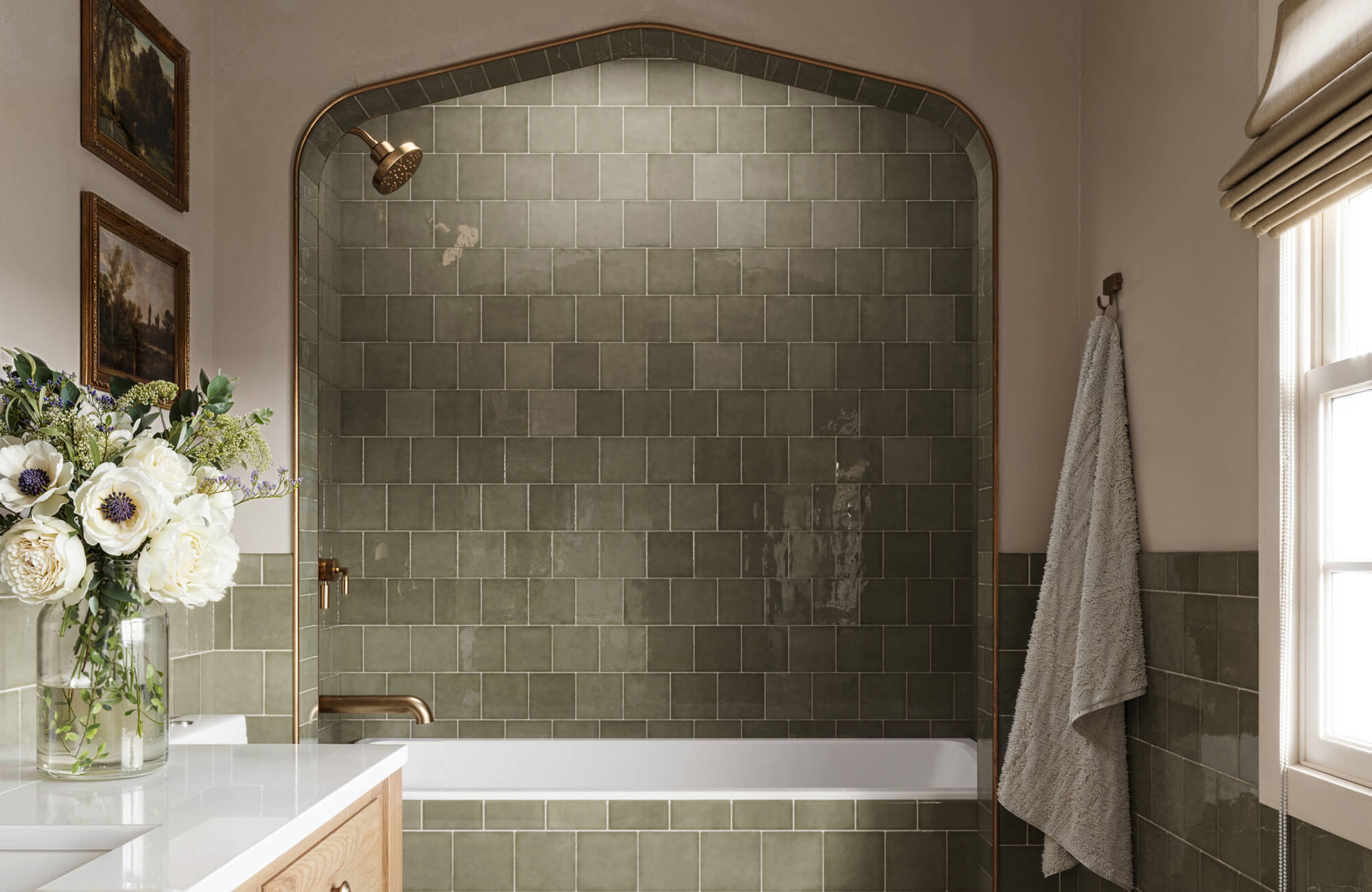 Elegant olive green square tiles envelop a cozy shower area with arched details, complemented by gold fixtures and natural light for a serene, timeless atmosphere.
