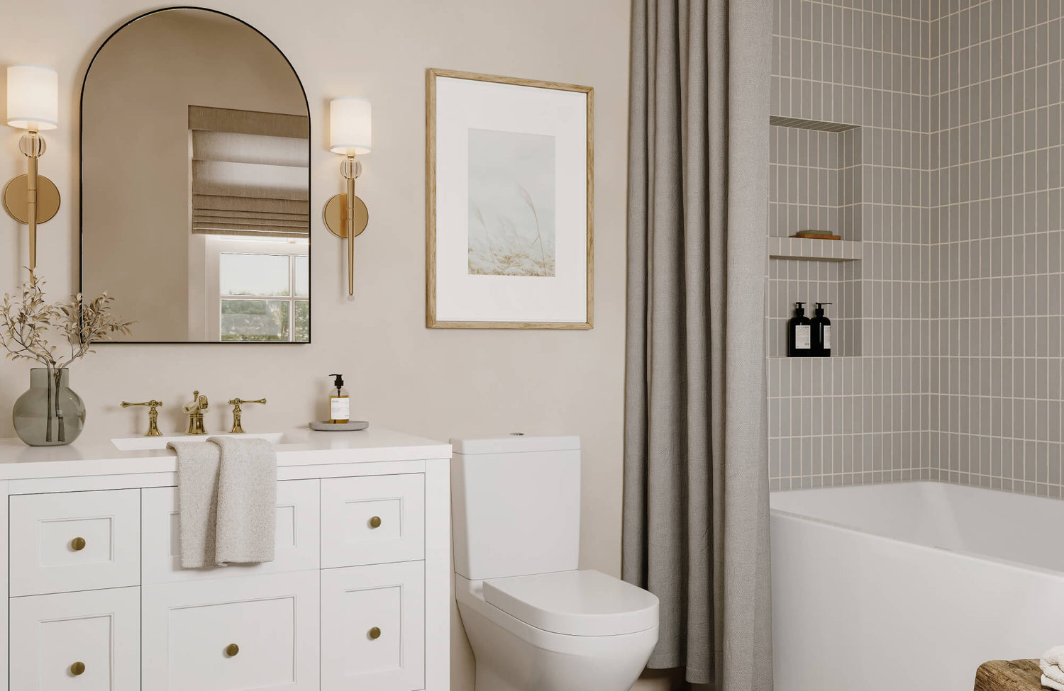 Neutral bathroom with white vanity, arched mirror, and gold sconces alongside soft gray shower tiles and linen curtain for a cozy, modern feel.