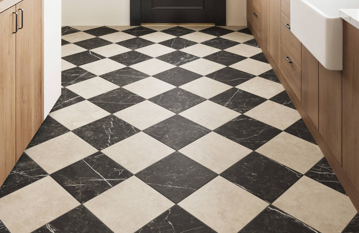 Close-up of a black and beige marble checkerboard tile floor in a modern kitchen with wood cabinetry and a black door.