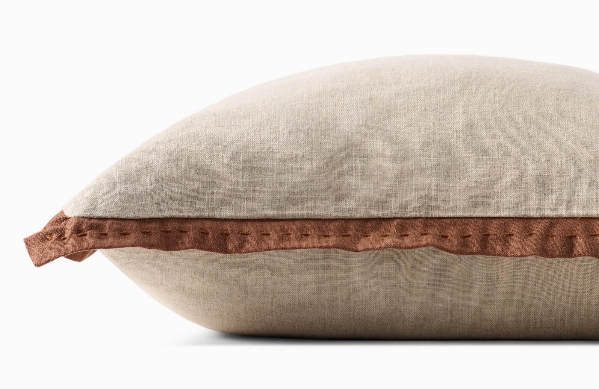 Neutral beige pillow with textured linen cover and soft terracotta trim, highlighting subtle gathered edging.