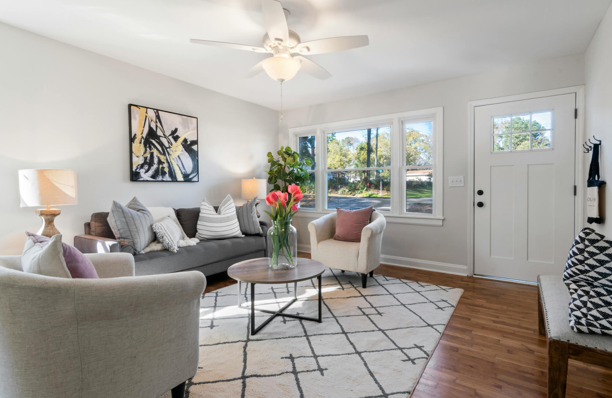 Bright living room with ceiling fan light, table lamps, and sunlight streaming through windows for balanced illumination.