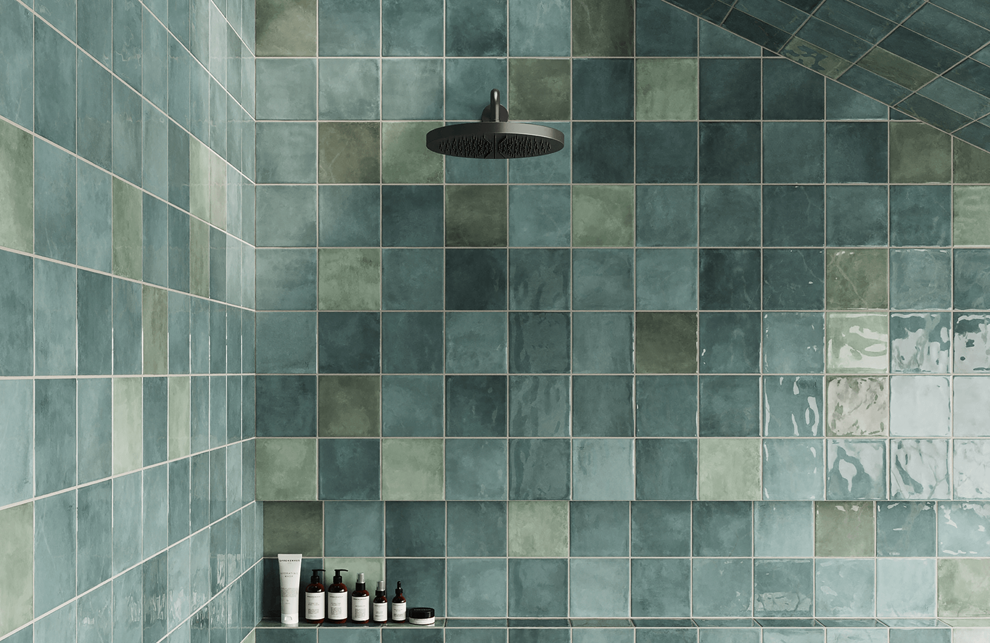Elegant shower space with glossy, handcrafted green bathroom tiles in varied shades, featuring a sleek black rainfall showerhead.