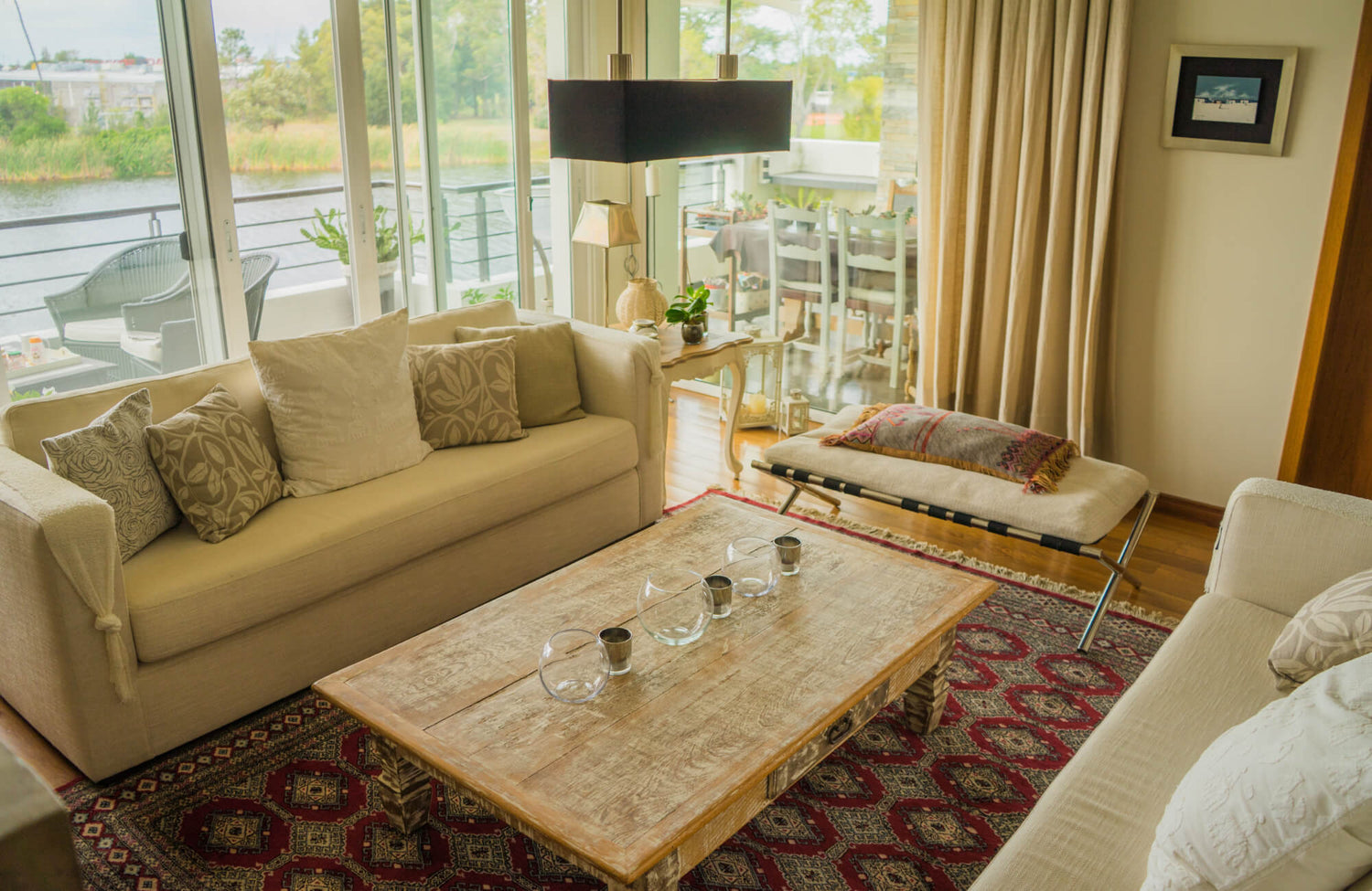Cozy living room with neutral sofas, a rustic wood coffee table, and a bold red patterned rug adding warmth and texture.