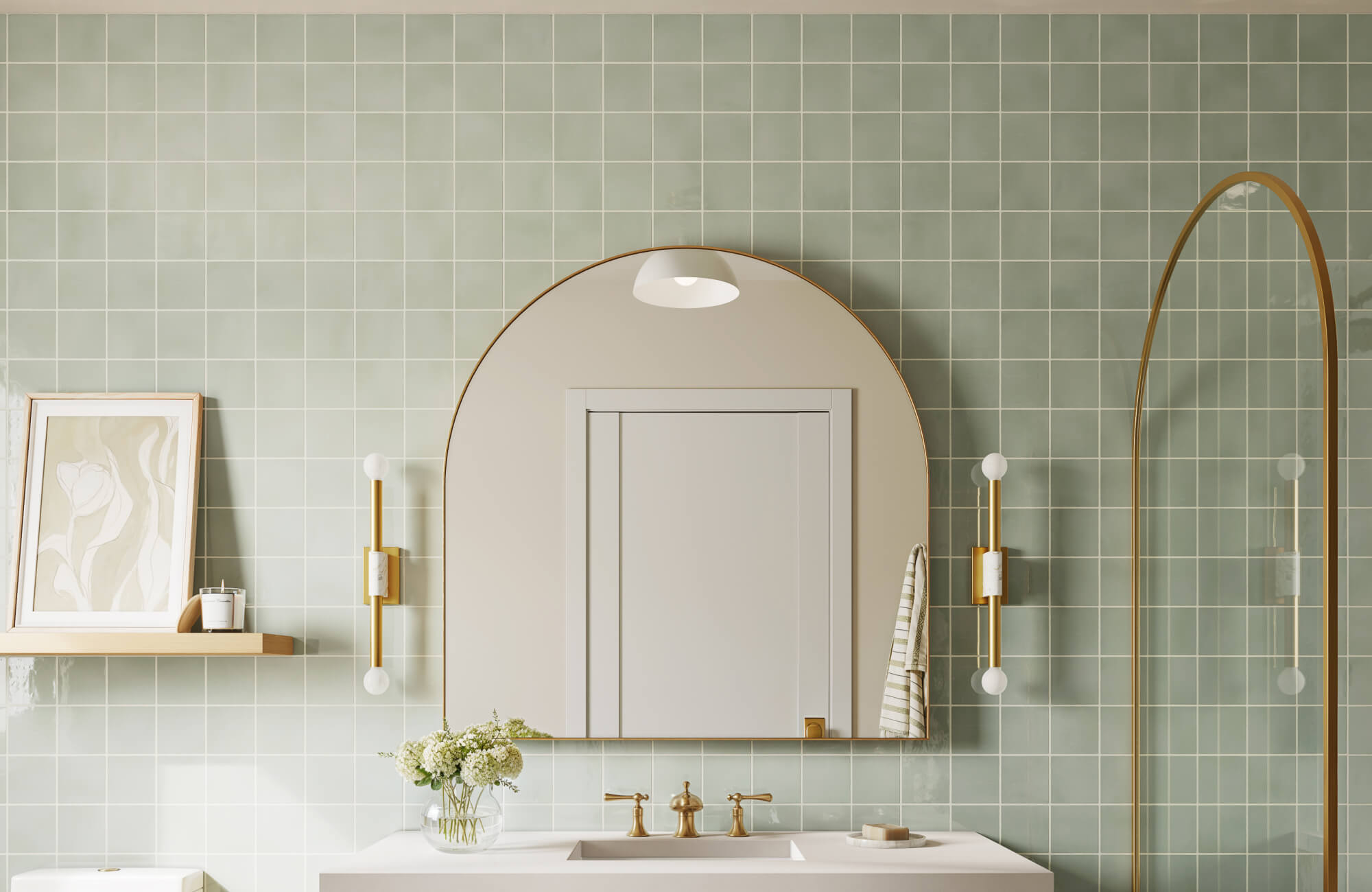 Modern bathroom vanity featuring a gold-framed arched mirror, brass fixtures, and green tiled walls with a minimal shelf accent.