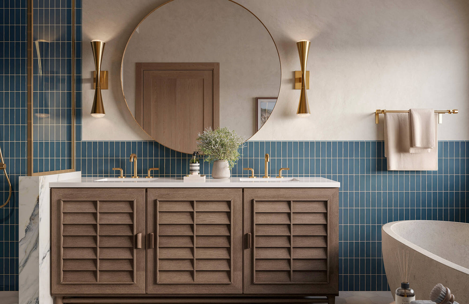 Modern bathroom with blue vertical subway tiles, round gold-framed mirror, brass sconces, and a wood vanity with shutter-style doors.