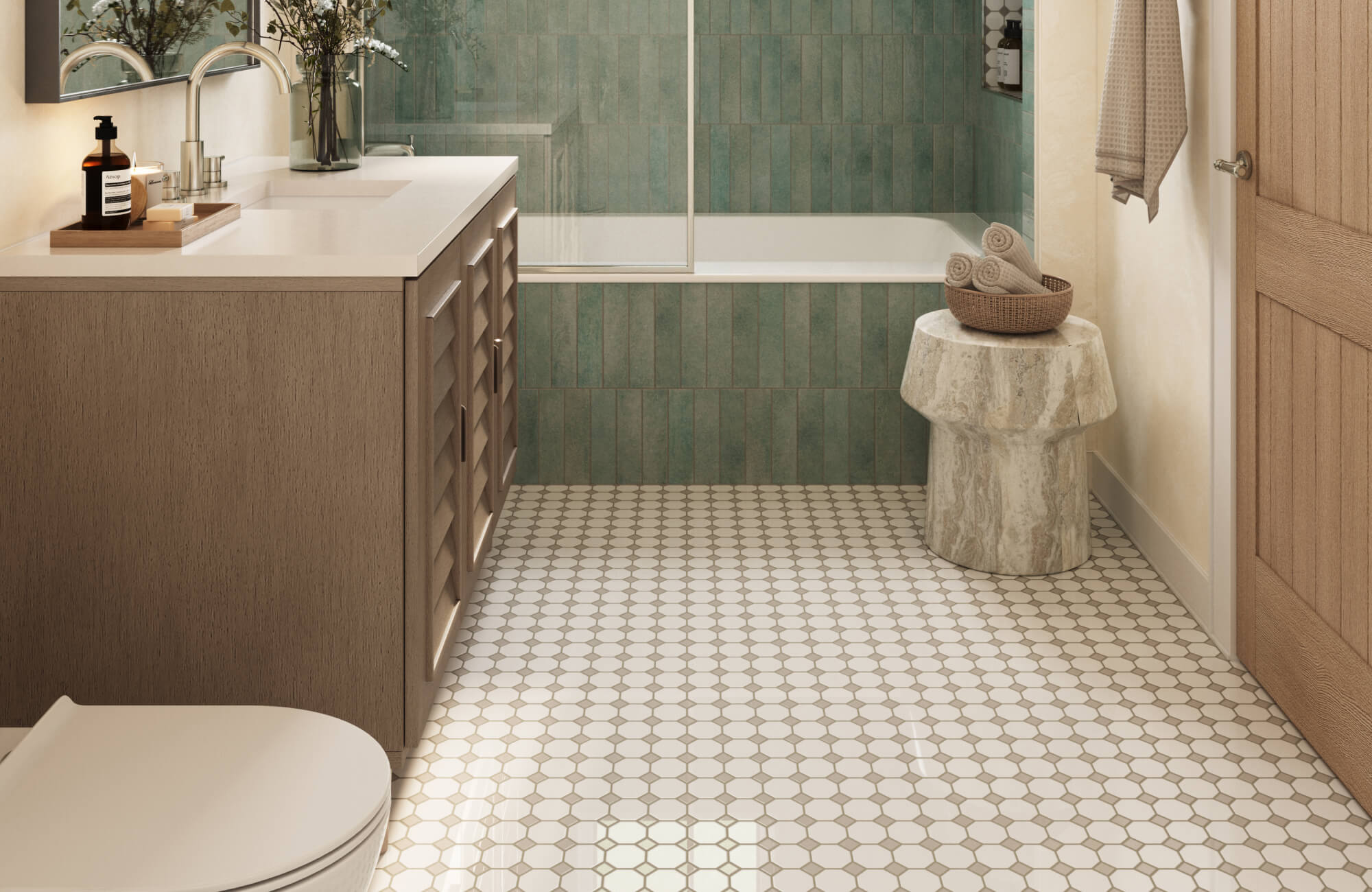 Sage green vertical shower subway tiles, white hex mosaic floor, warm wood vanity, and sculptural stone stool in a serene bathroom.