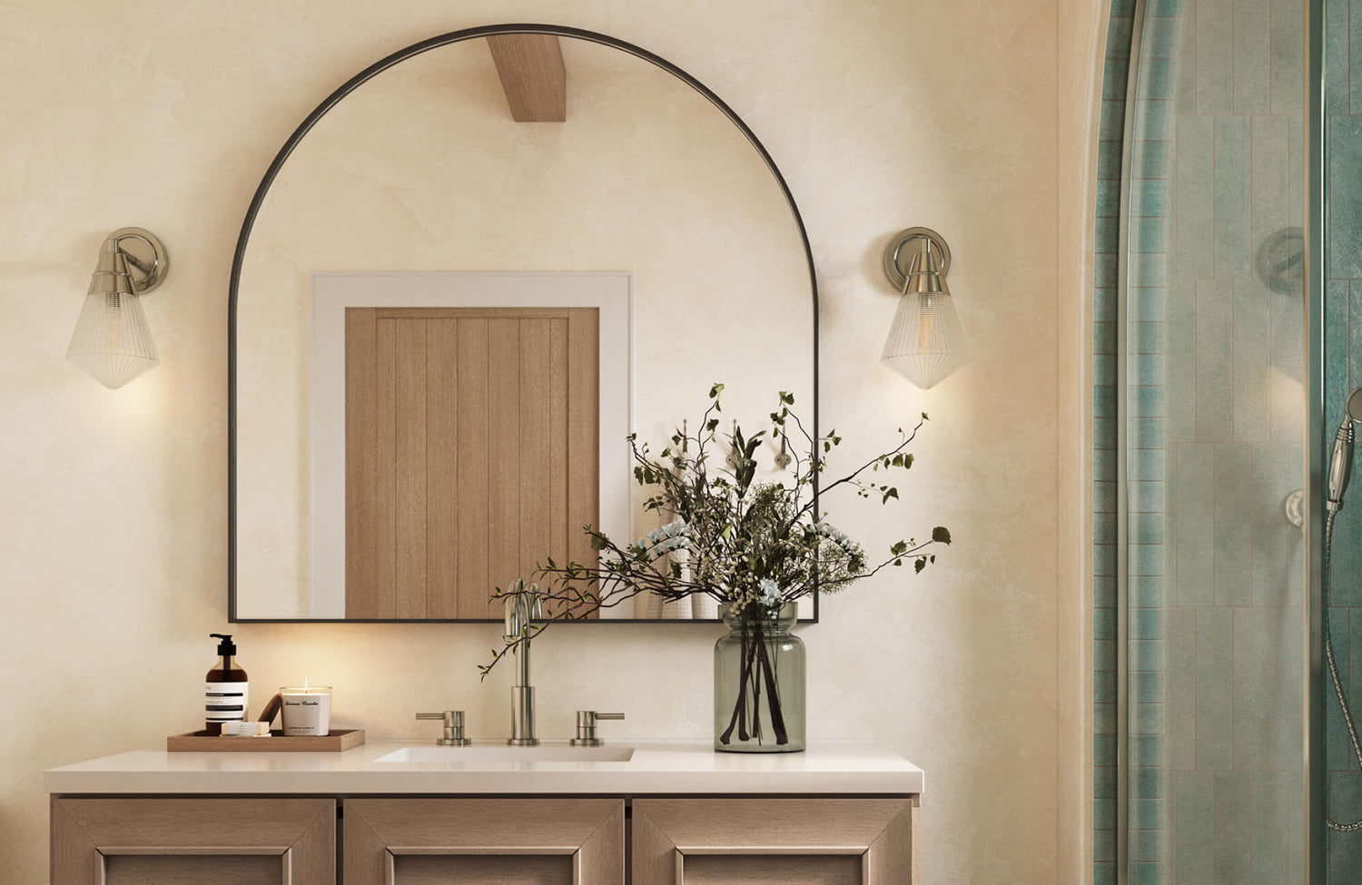 Bathroom vanity styled with an arch mirror centered above the sink, softly framed by wall sconces and warm neutral finishes.