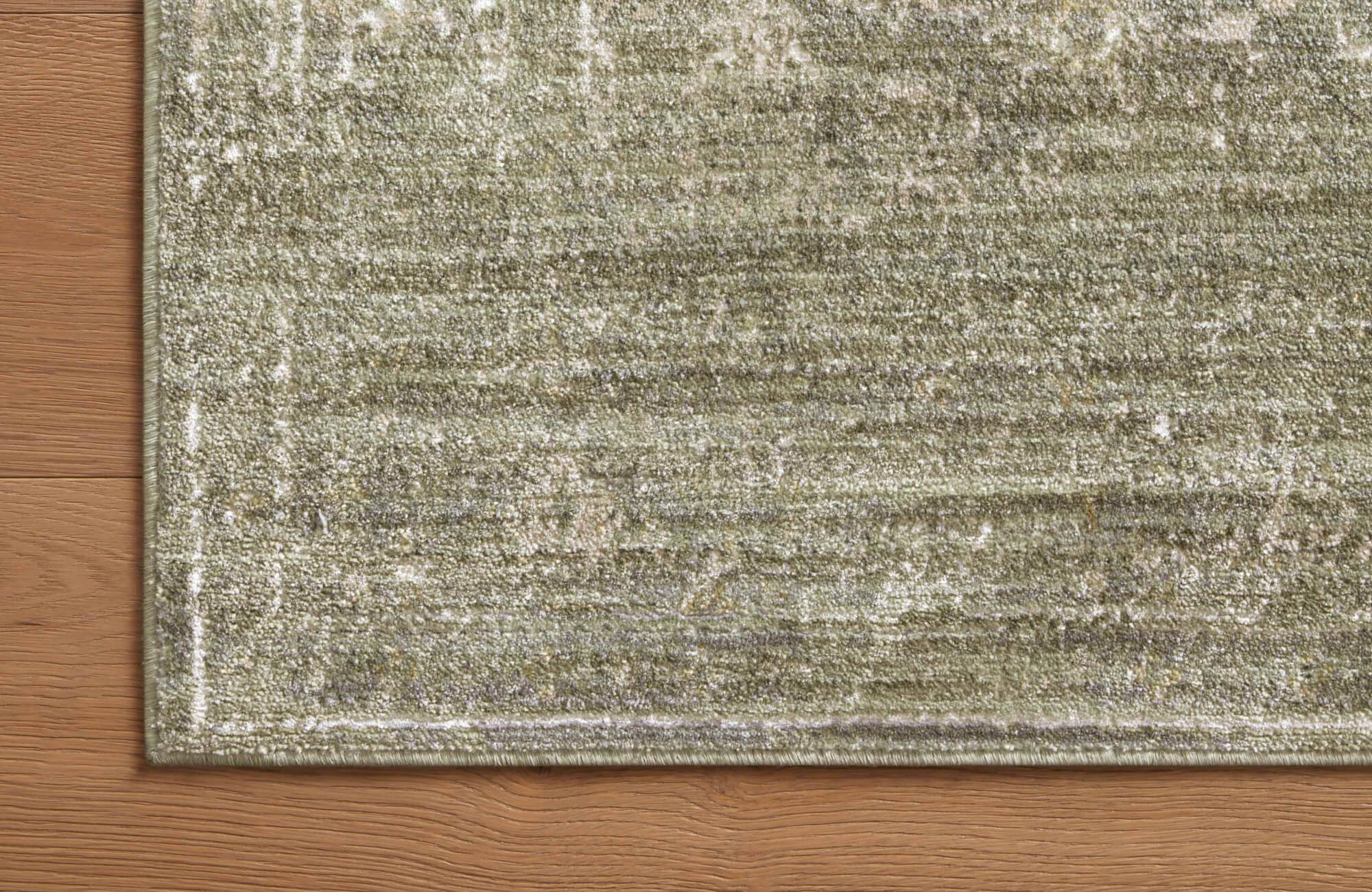 A rug featuring a soft polyester-polypropylene blend with a distressed pattern in beige and grayish-green hues with subtle yellow gold accents.