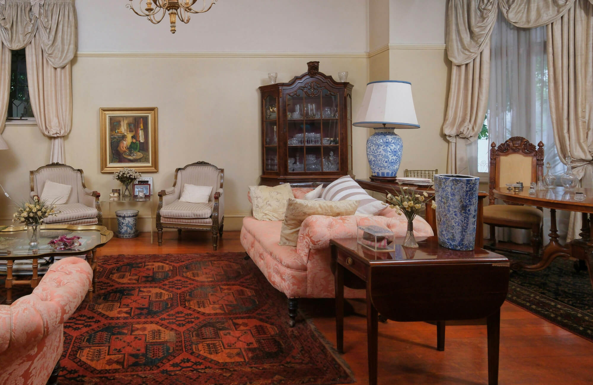 Elegant living room with a Moroccan rug in deep red and black geometric patterns, highlighted by a classic chandelier that provides warm ambient lighting.