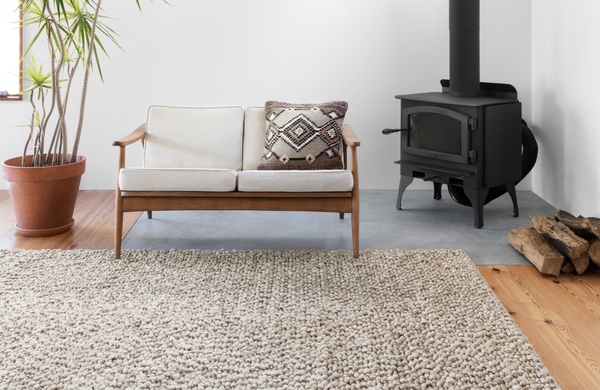 Cozy living space with a chunky wool rug, wooden furniture, and a fireplace, highlighting soft indoor textures.