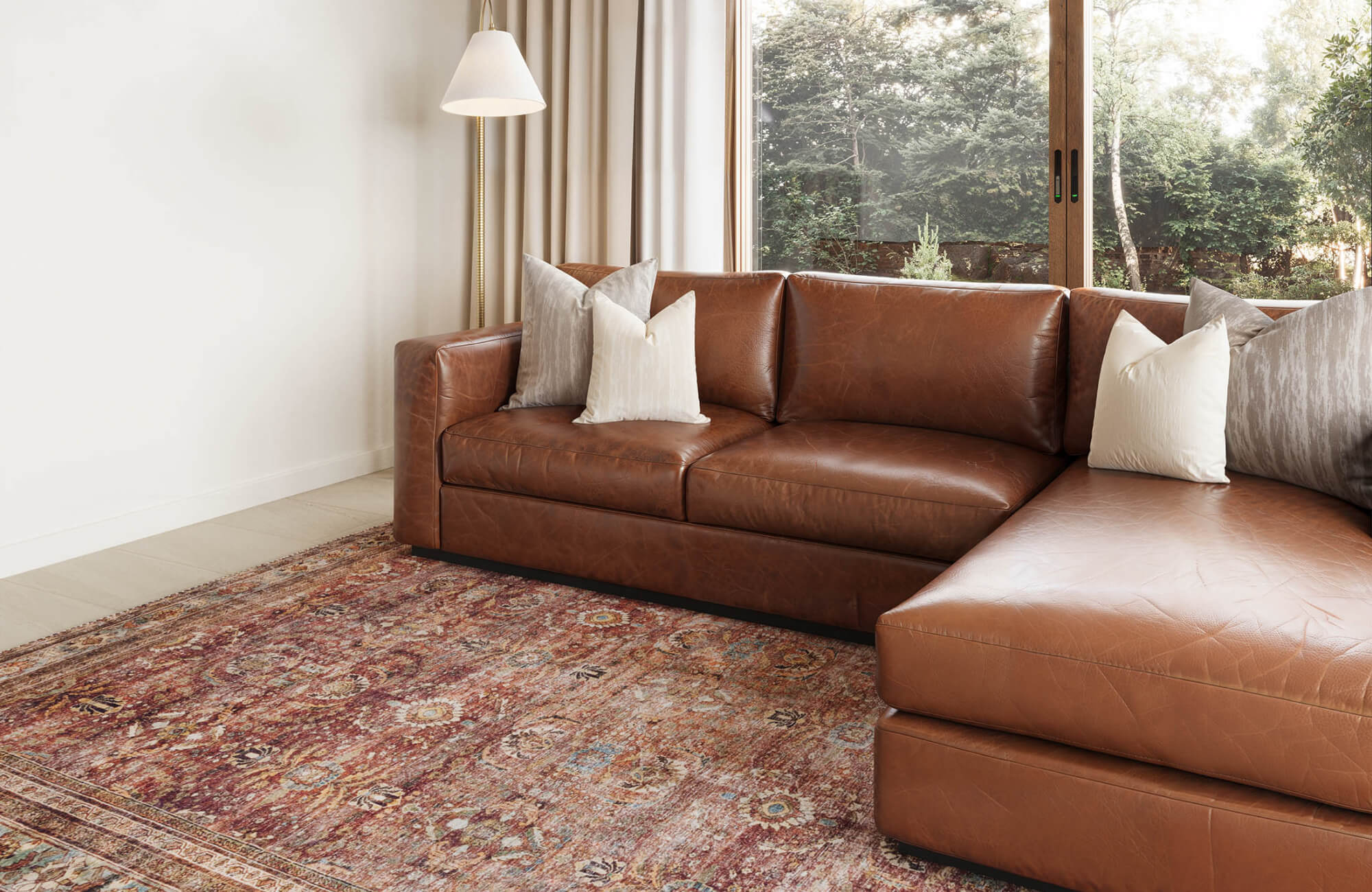 Warm and inviting living space featuring a rich brown leather sectional and a vintage-inspired 9x12 area rug in earthy tones.