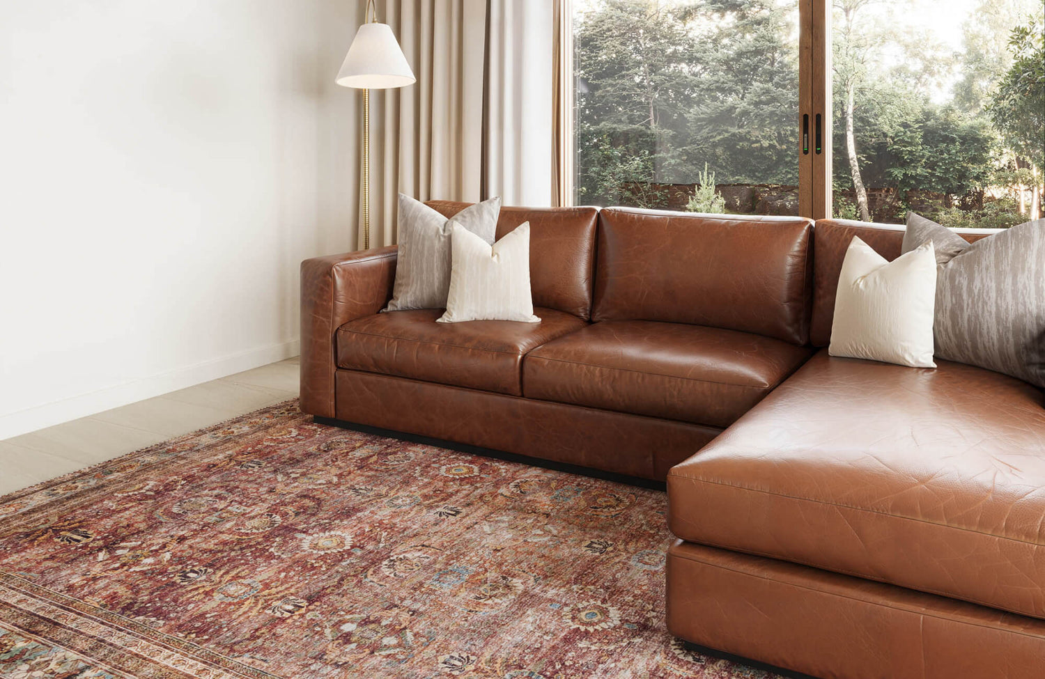 Warm and inviting living space featuring a rich brown leather sectional and a vintage-inspired 9x12 area rug in earthy tones.