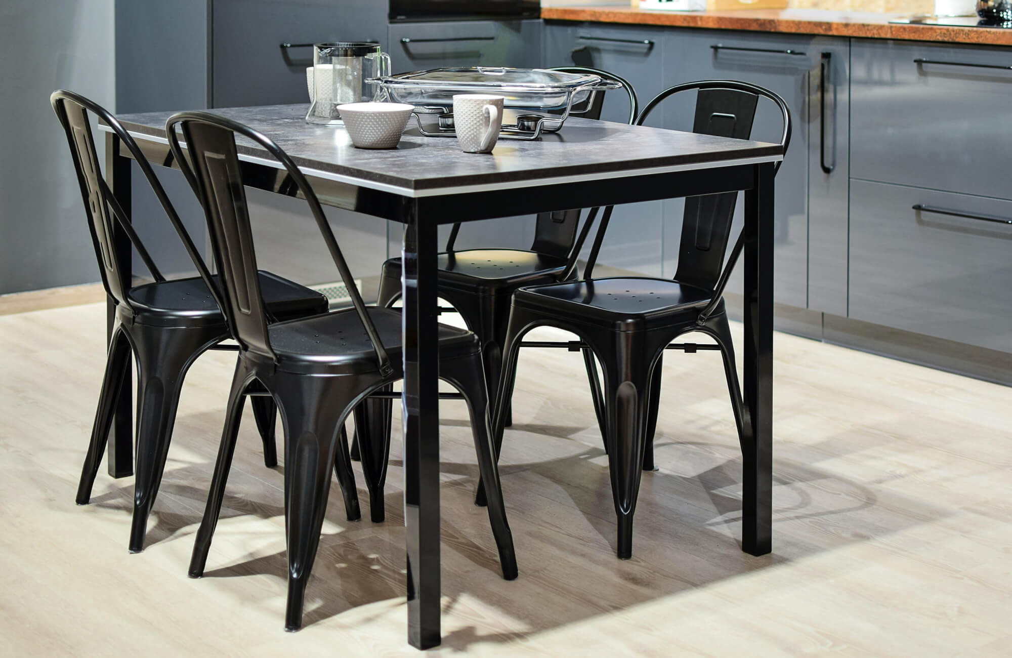 Sleek black metal dining set on pale wood-look tiles, creating a striking contrast in a modern kitchen space.