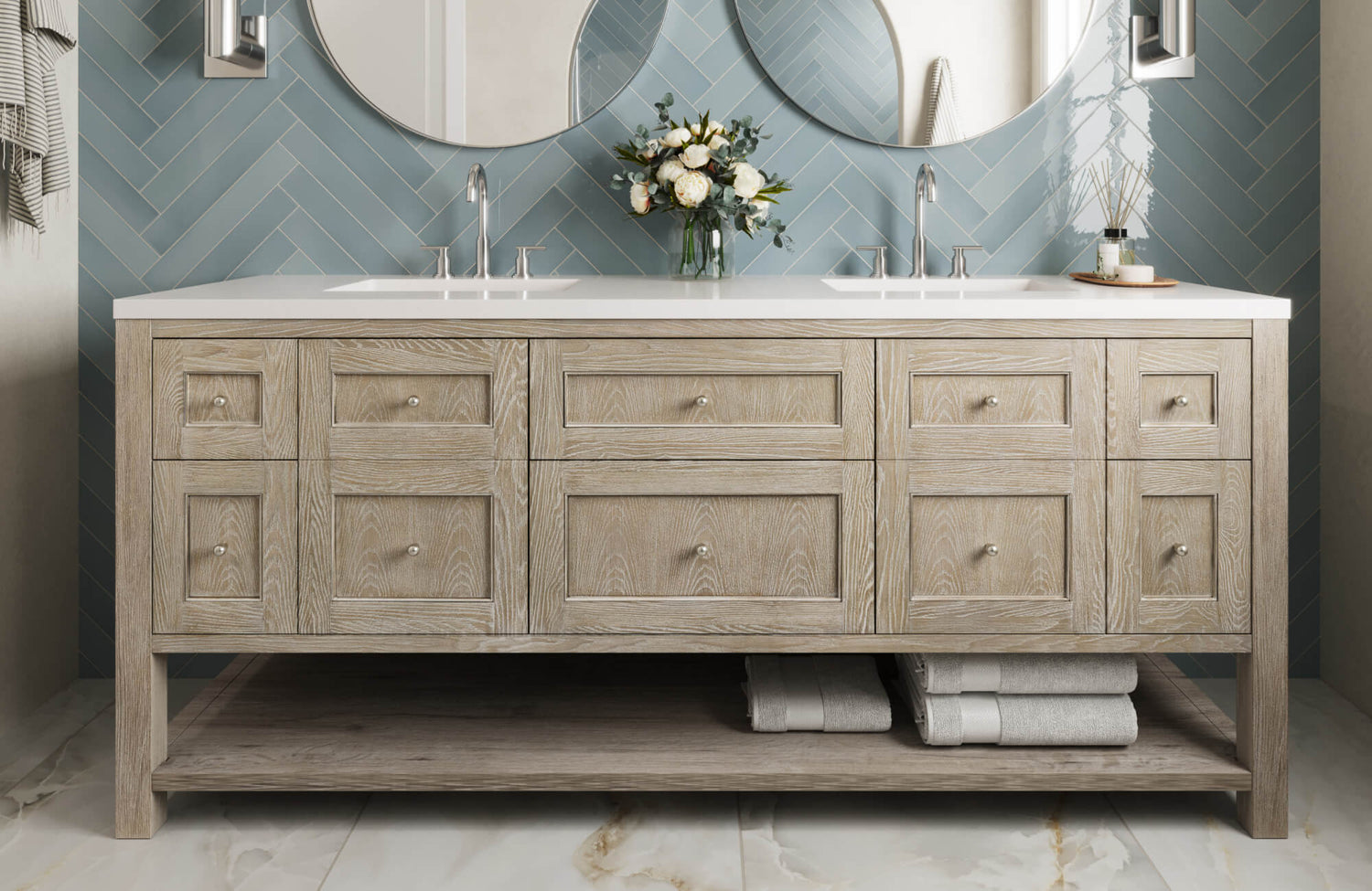 Light wood vanity with double sinks pairs beautifully with blue herringbone wall tiles and marble look flooring for a fresh spa vibe.