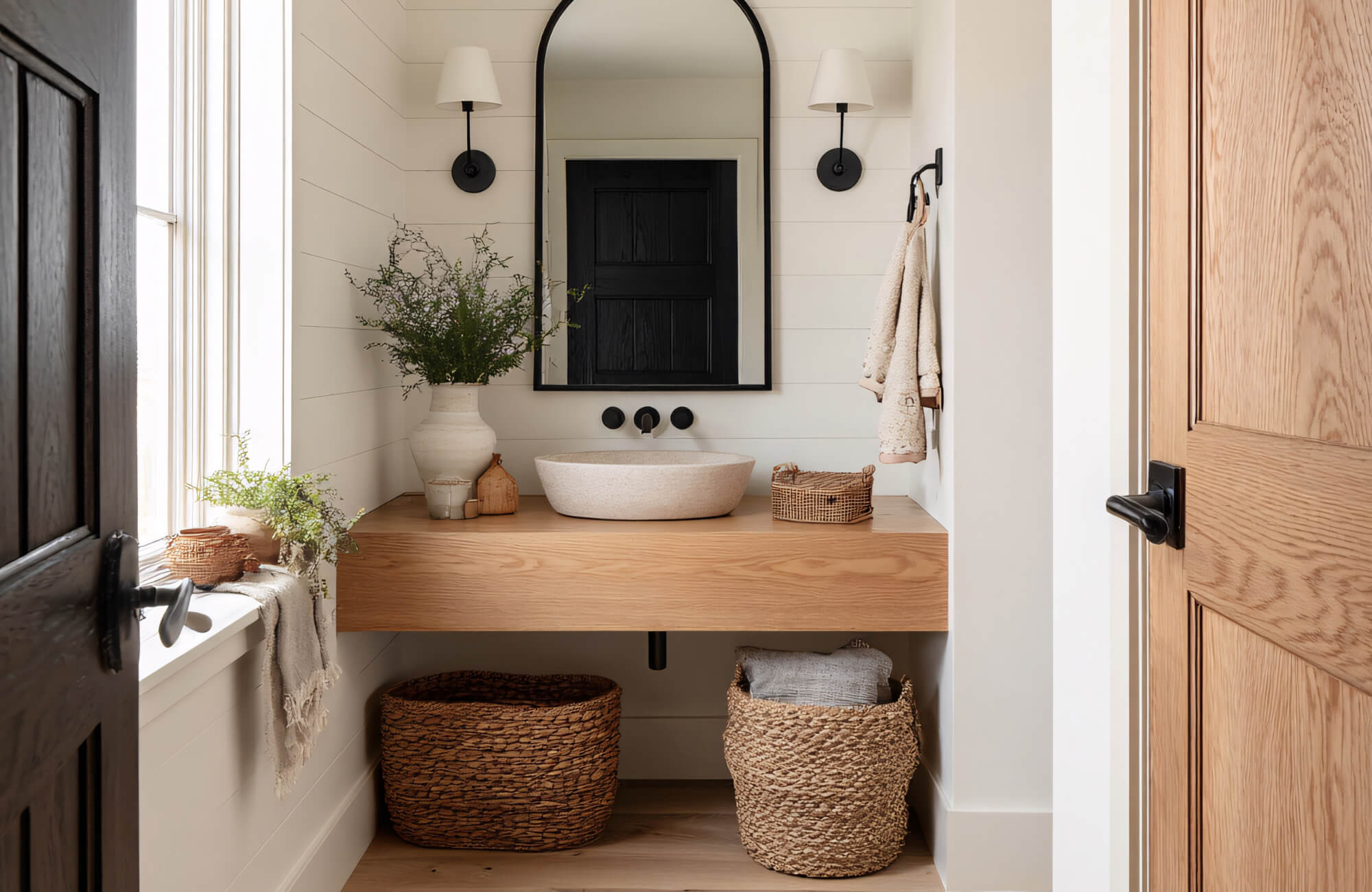 Bathroom vanity with a large black arched mirror, wood countertop, vessel sink, and neutral finishes creating a warm, timeless look.