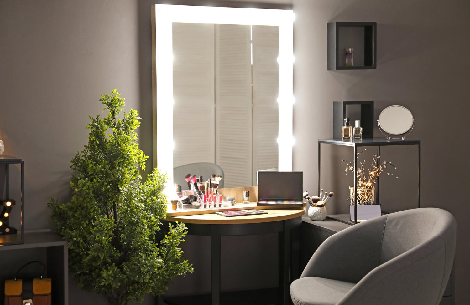 A lighted vanity mirror illuminating a makeup station with brushes, palettes, and decor in a modern, softly lit room.