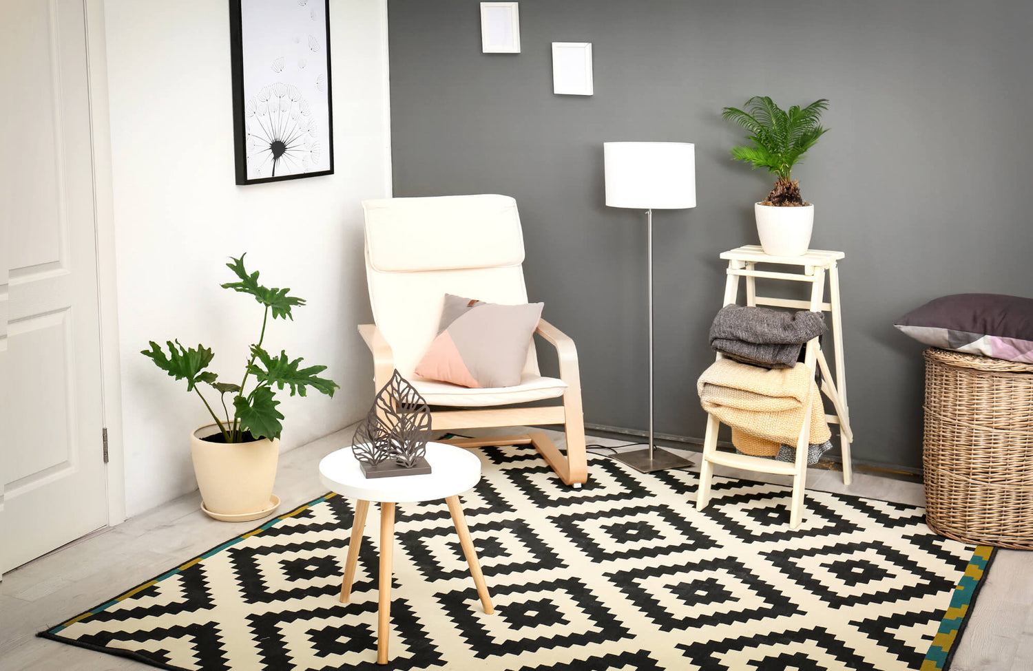 Cozy modern living space with a black and white geometric rug, neutral chair, indoor plants, and soft textiles against a gray accent wall.