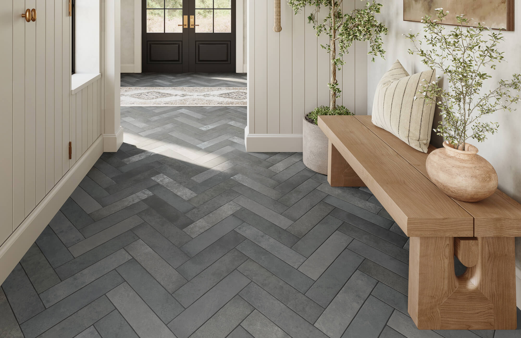 Entryway with gray herringbone floor tiles, a wooden bench, and potted plants creating a warm, welcoming contrast.