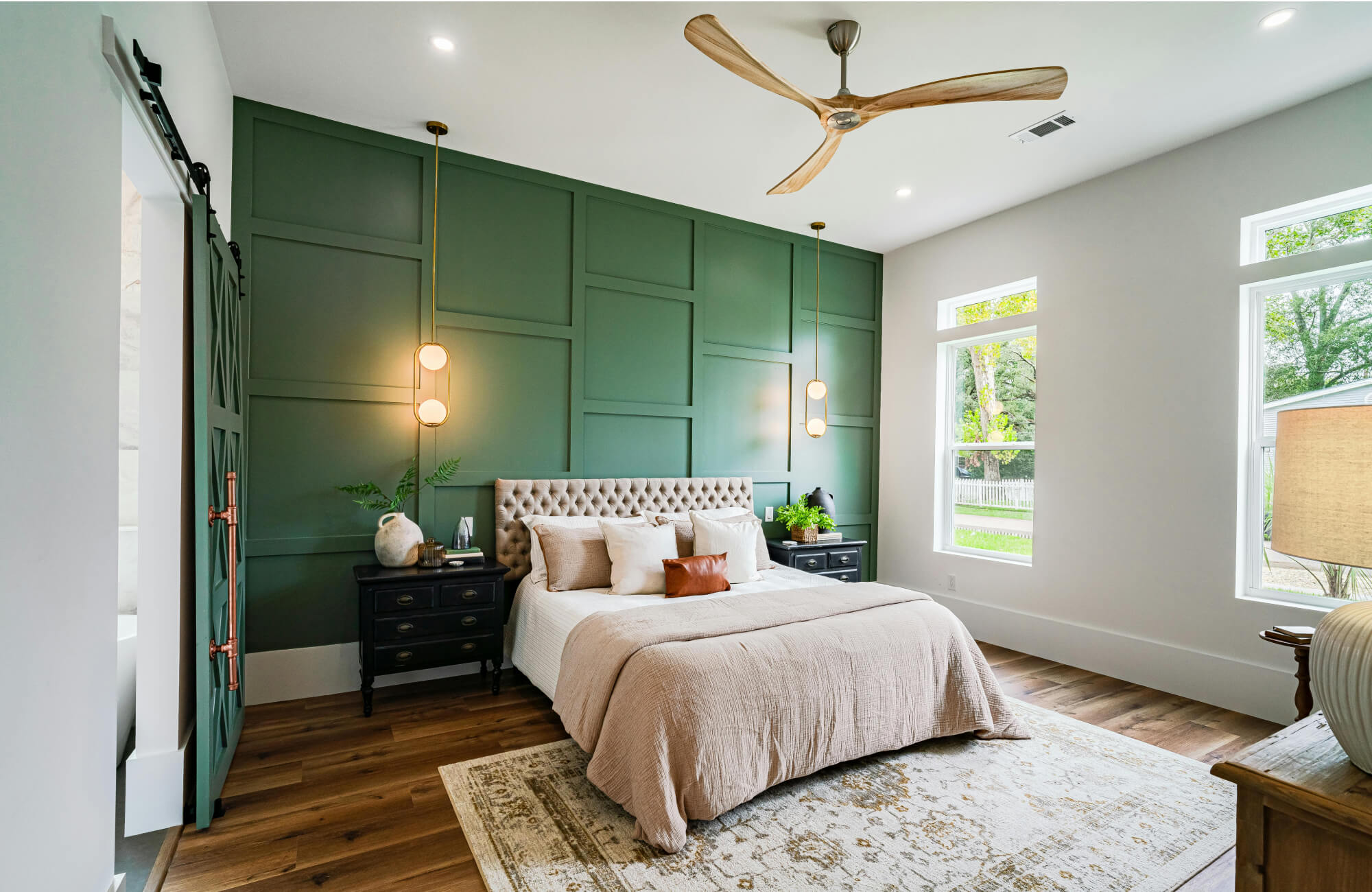 Bedroom with a light beige rug enhancing warmth against a green accent wall and wood flooring.