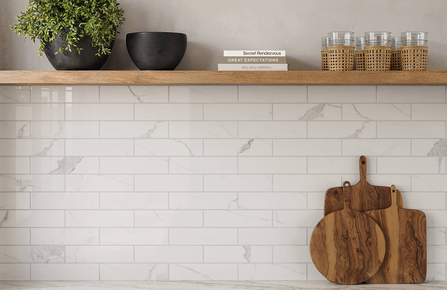 Kitchen backsplash featuring marble-look subway tiles, a wooden shelf with books and glasses, and wooden cutting boards.