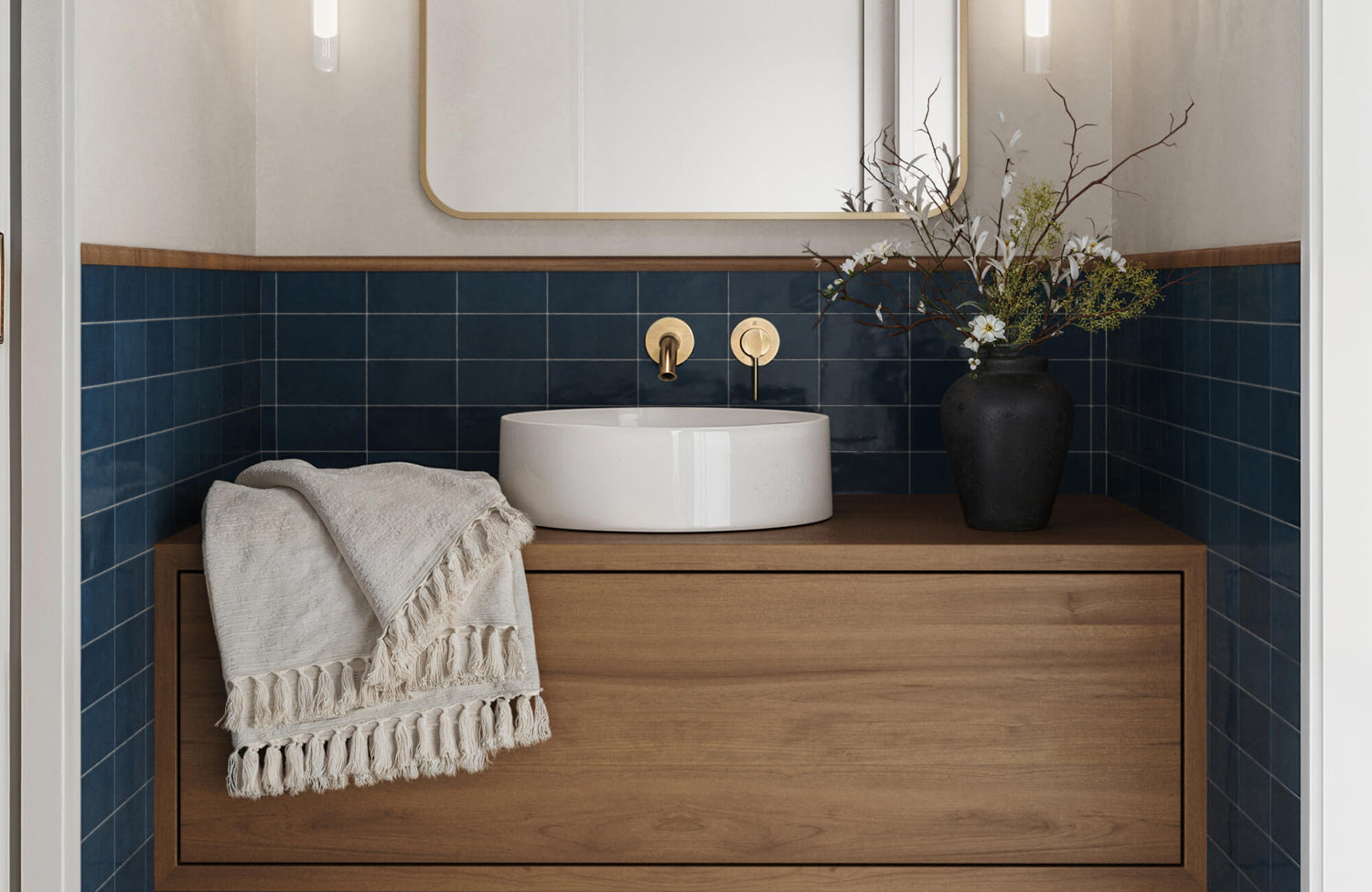 Elegant bathroom vanity with deep blue backsplash tiles, a round white vessel sink, and brass fixtures on a warm wood cabinet.