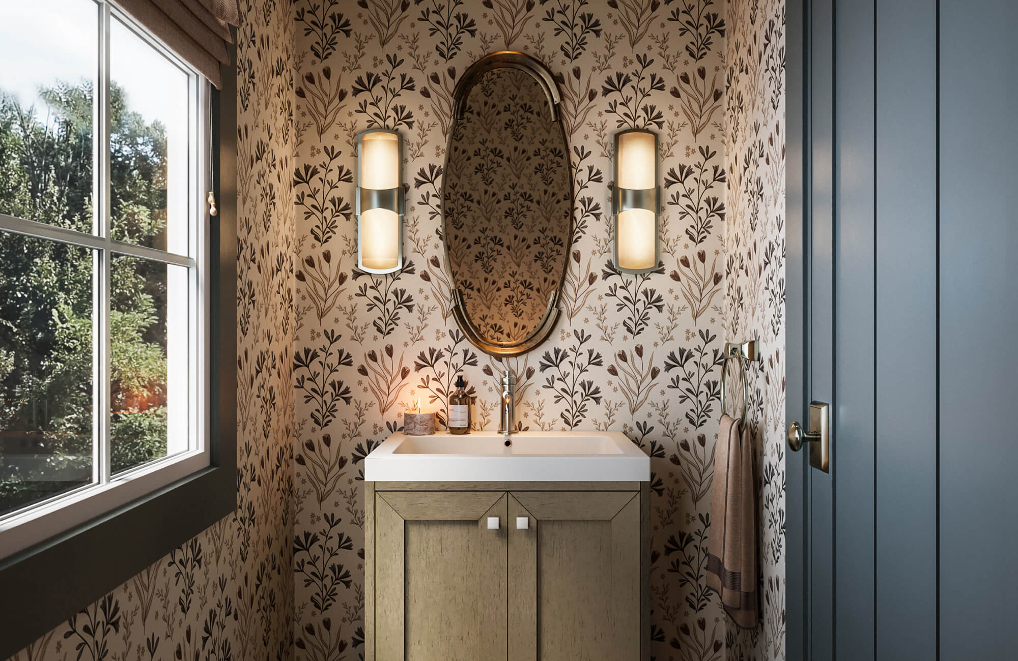 Floral botanical wallpaper in a small powder room featuring a light wood vanity, white sink, oval brass mirror, and modern wall sconces.