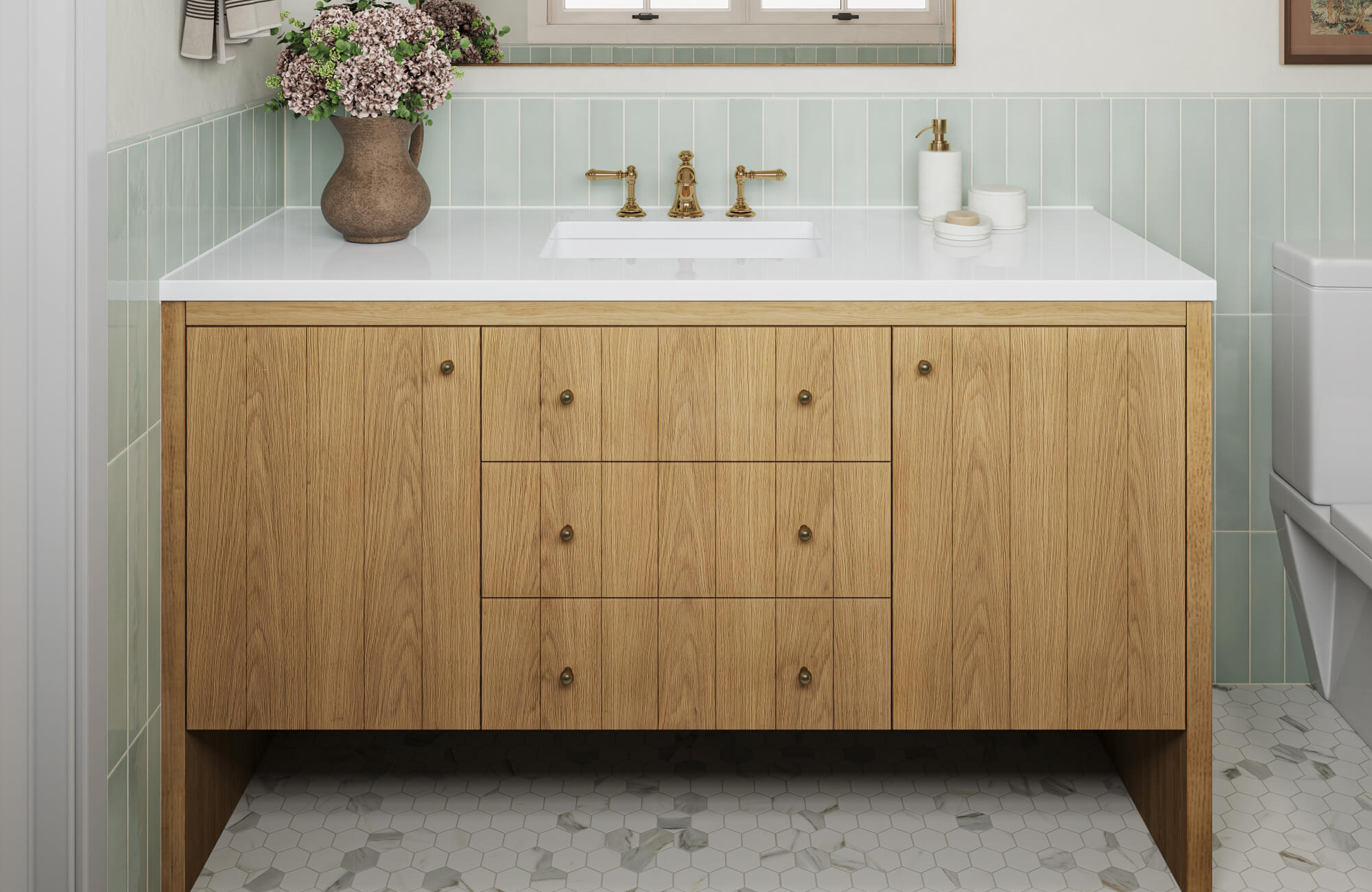 A white oak bathroom vanity with a crisp white countertop, paired with soft green wall tile and light hexagon floor tiles that keep the space feeling bright and balanced.