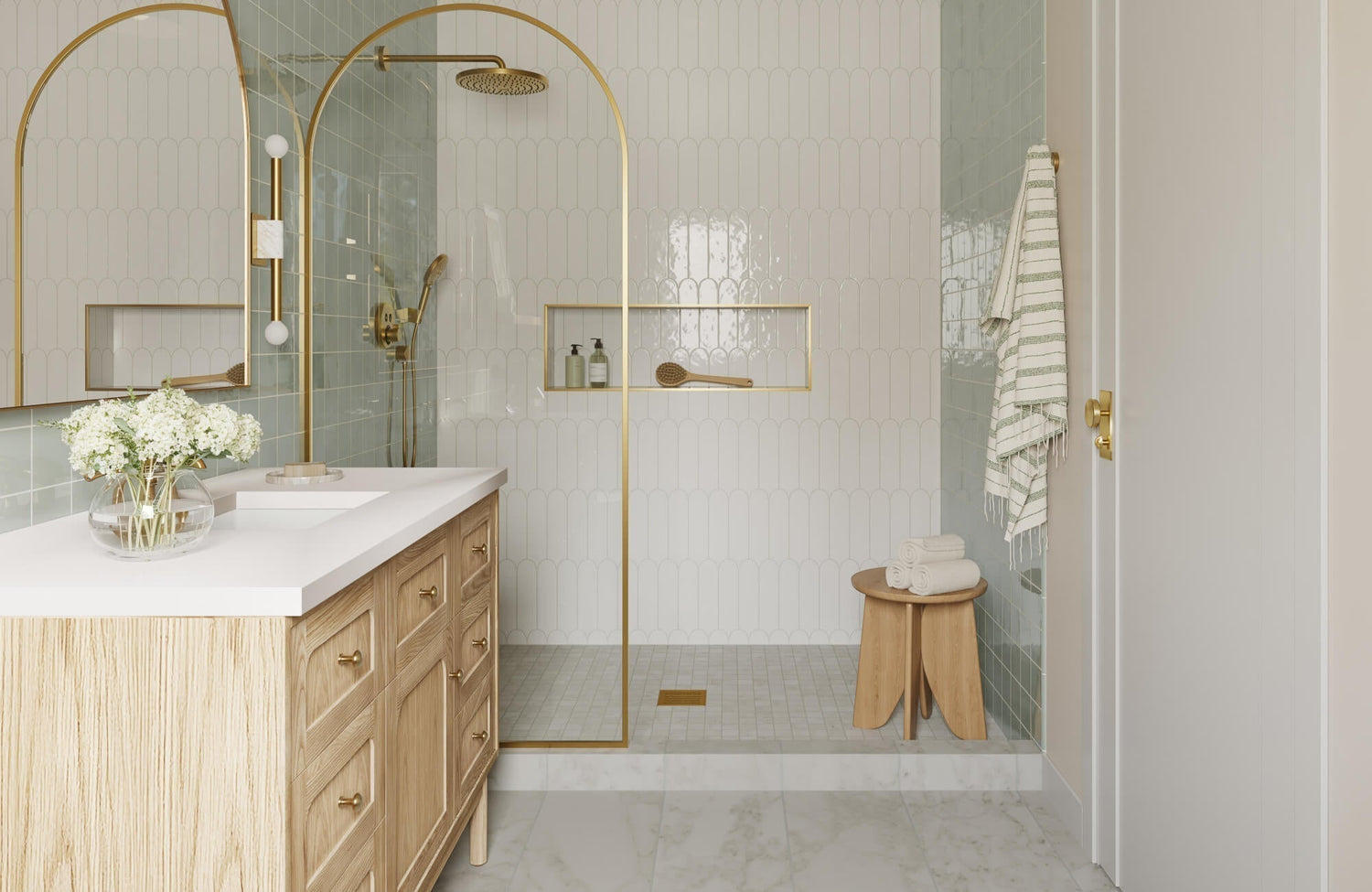 Elegant bathroom with scalloped white wall tiles, pale green glazed accents, and brushed gold fixtures for a refined, spa-like retreat.