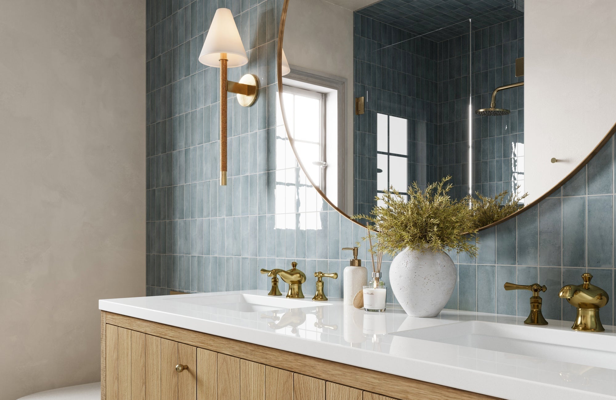 Brass-accented round mirror above double sink with blue tile backsplash in a warm-toned, modern bathroom.