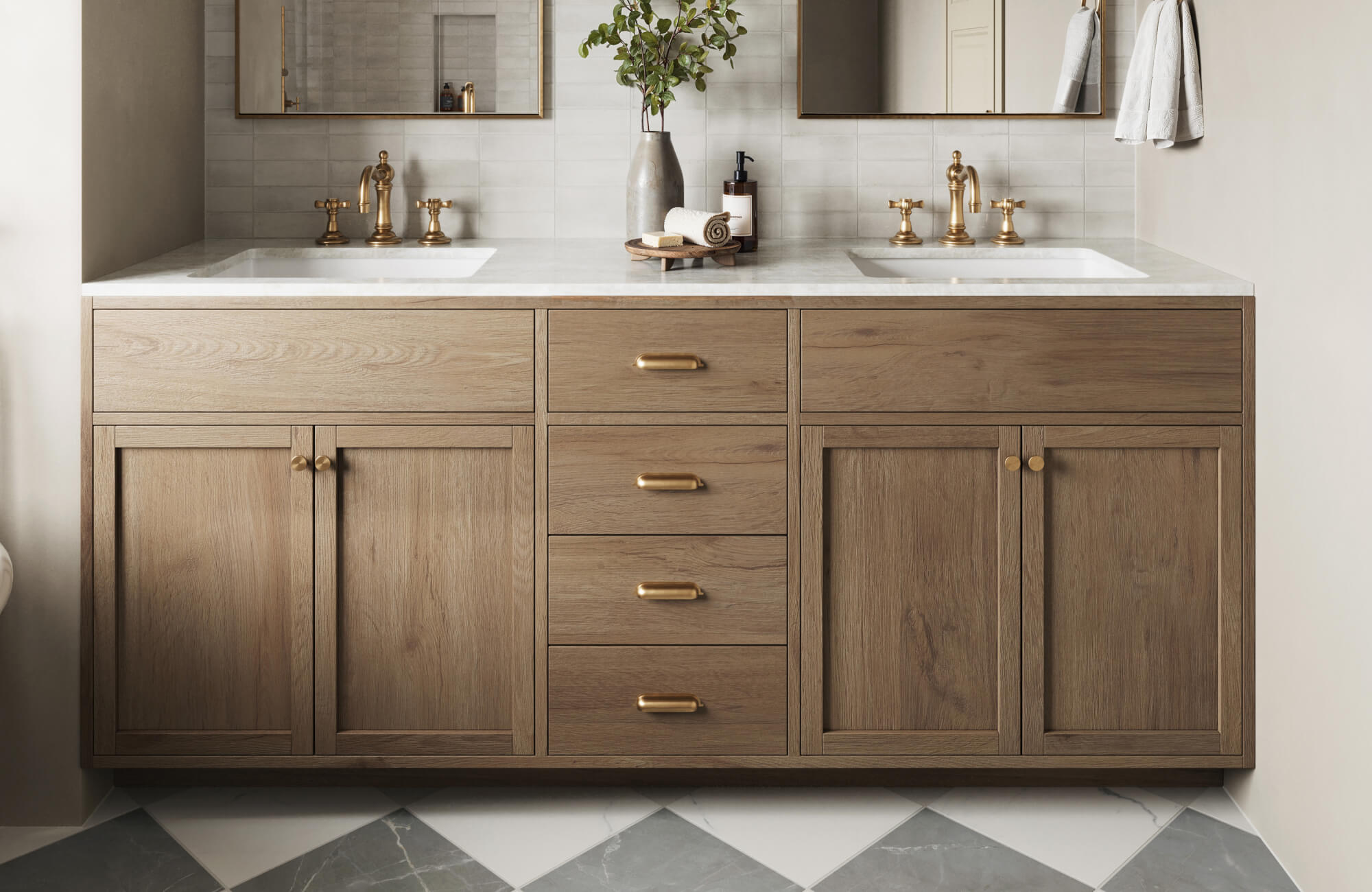 Bathroom featuring light oak double vanity with brass hardware, white countertops, and gray diamond-patterned tile floor for modern contrast