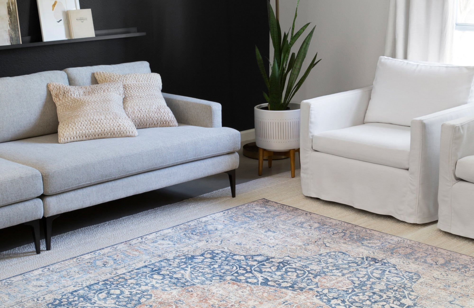Light blue and white furniture paired with a patterned rug that contrasts both sofa and wall tones.