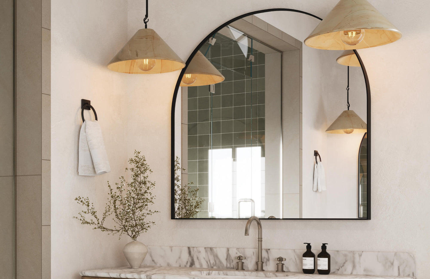 Arched black-framed mirror above marble vanity, accented by cone pendant lights and brushed nickel faucet.