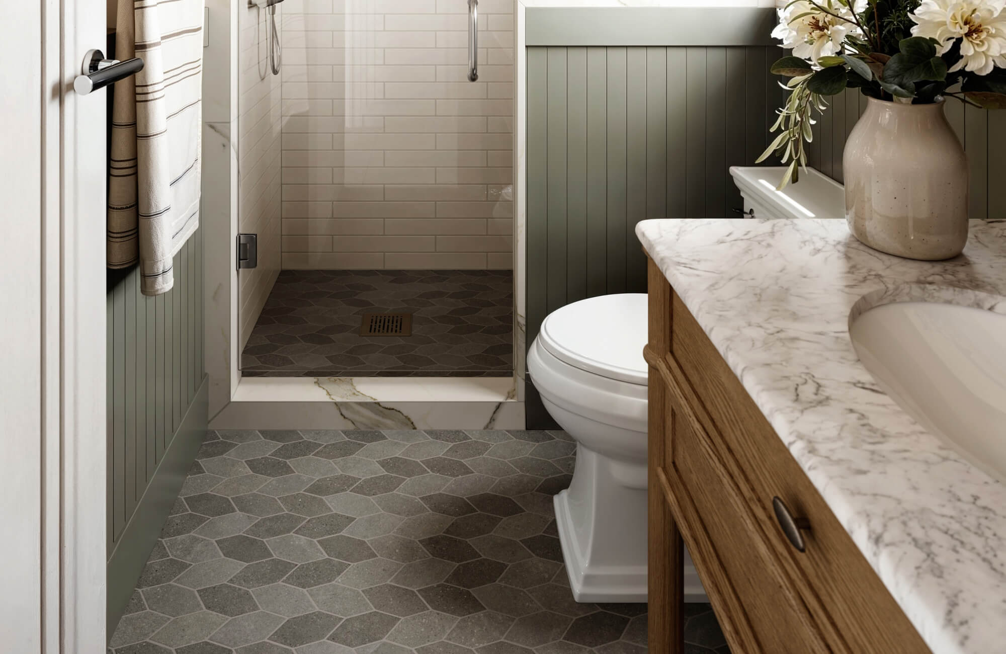 Earth-toned hexagon tiles flow into a walk-in shower with white subway walls and a marble threshold accent.
