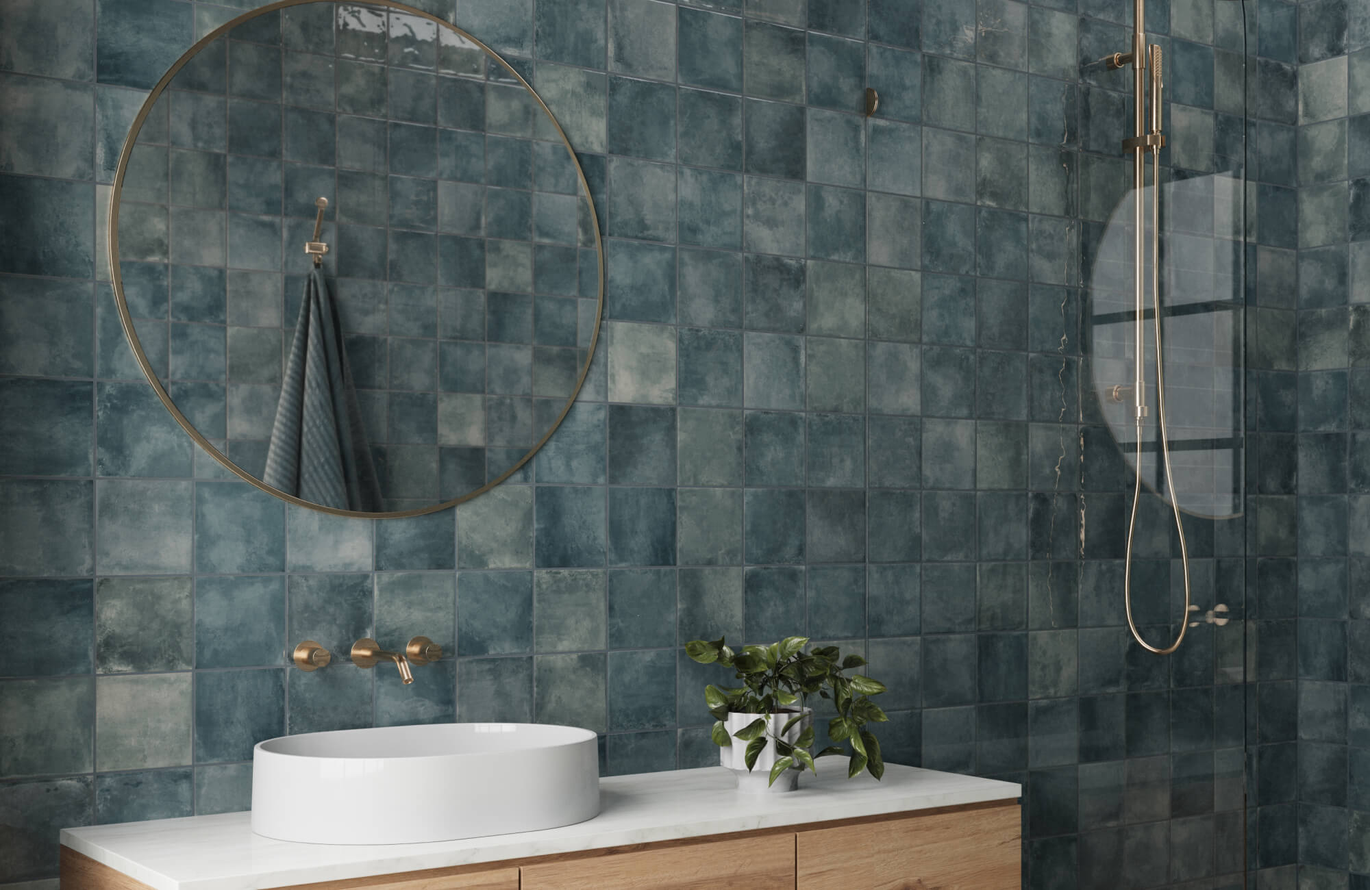 Sleek bathroom with glossy deep blue square tiles, a round brass-framed mirror, and a modern gold shower fixture.