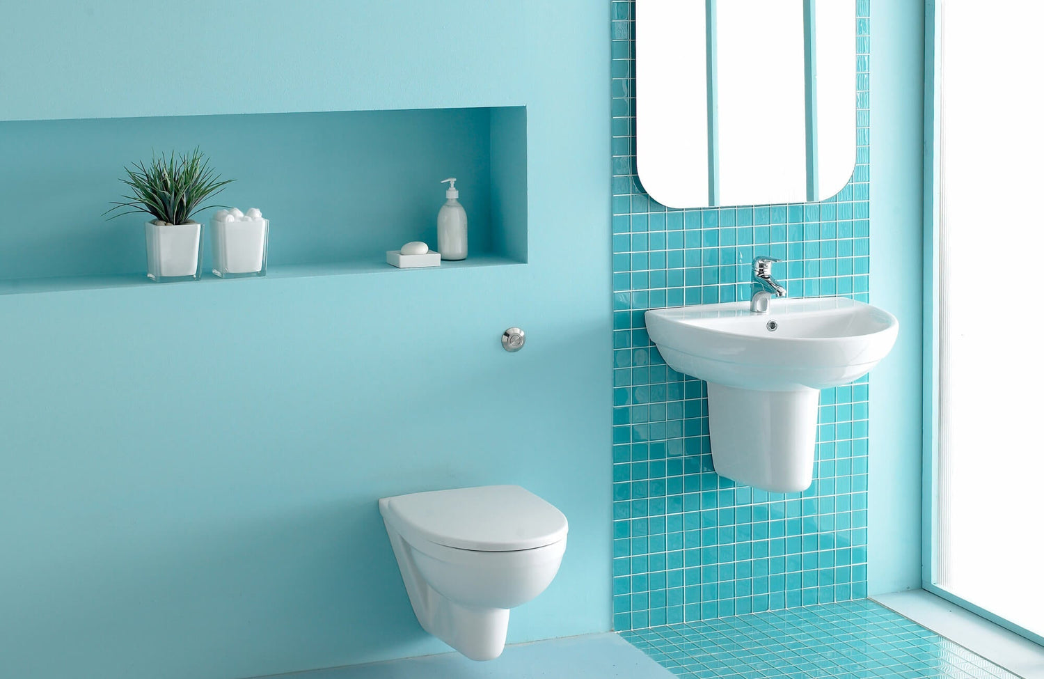 Modern light blue bathroom with glossy mosaic tile accents, floating sink, and built-in wall shelf featuring minimal white decor.